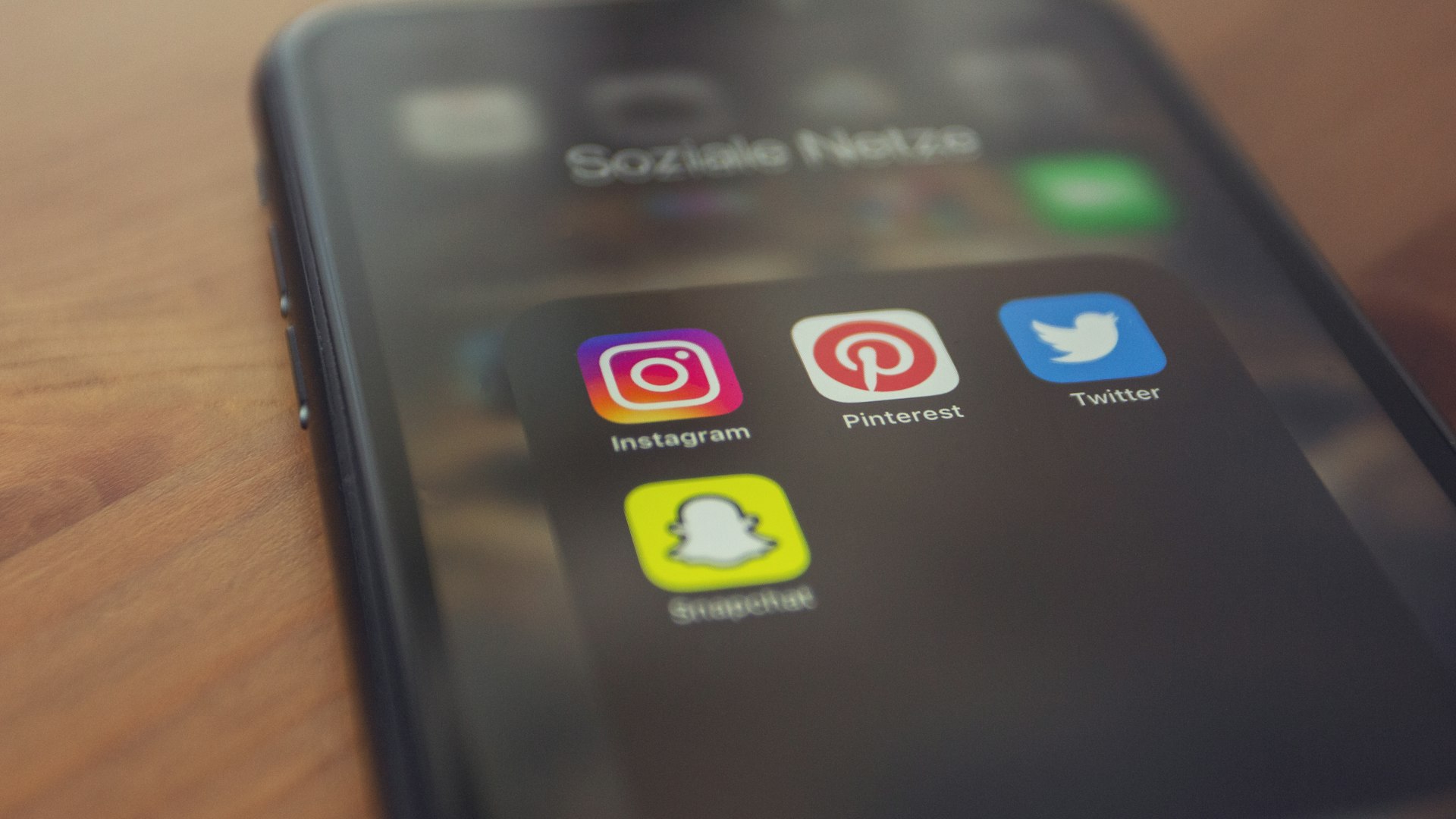 Smartphone on a wooden table showing social media app icons