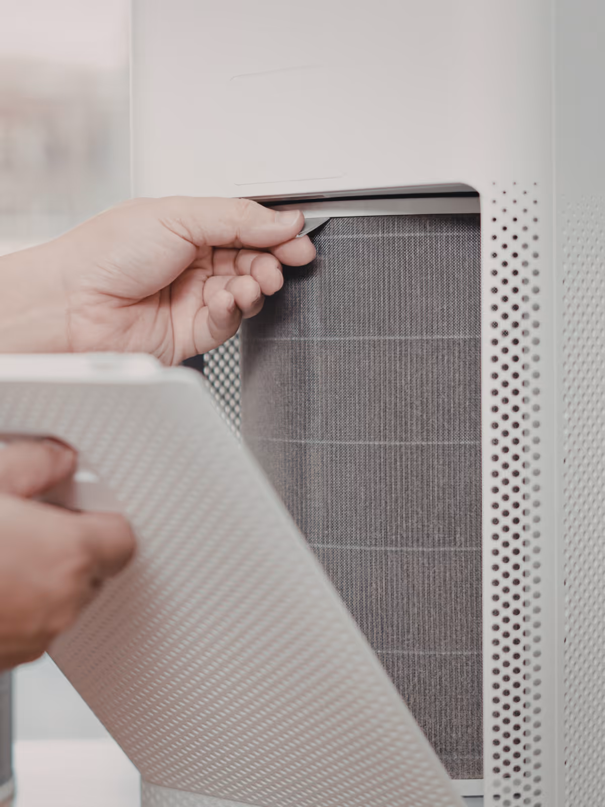 Person opening a white air purifier to access the internal filter.