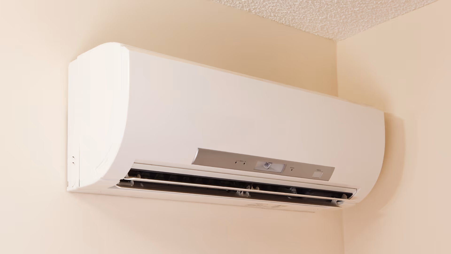 Wall-mounted white ductless mini-split air conditioning unit installed in a room corner.