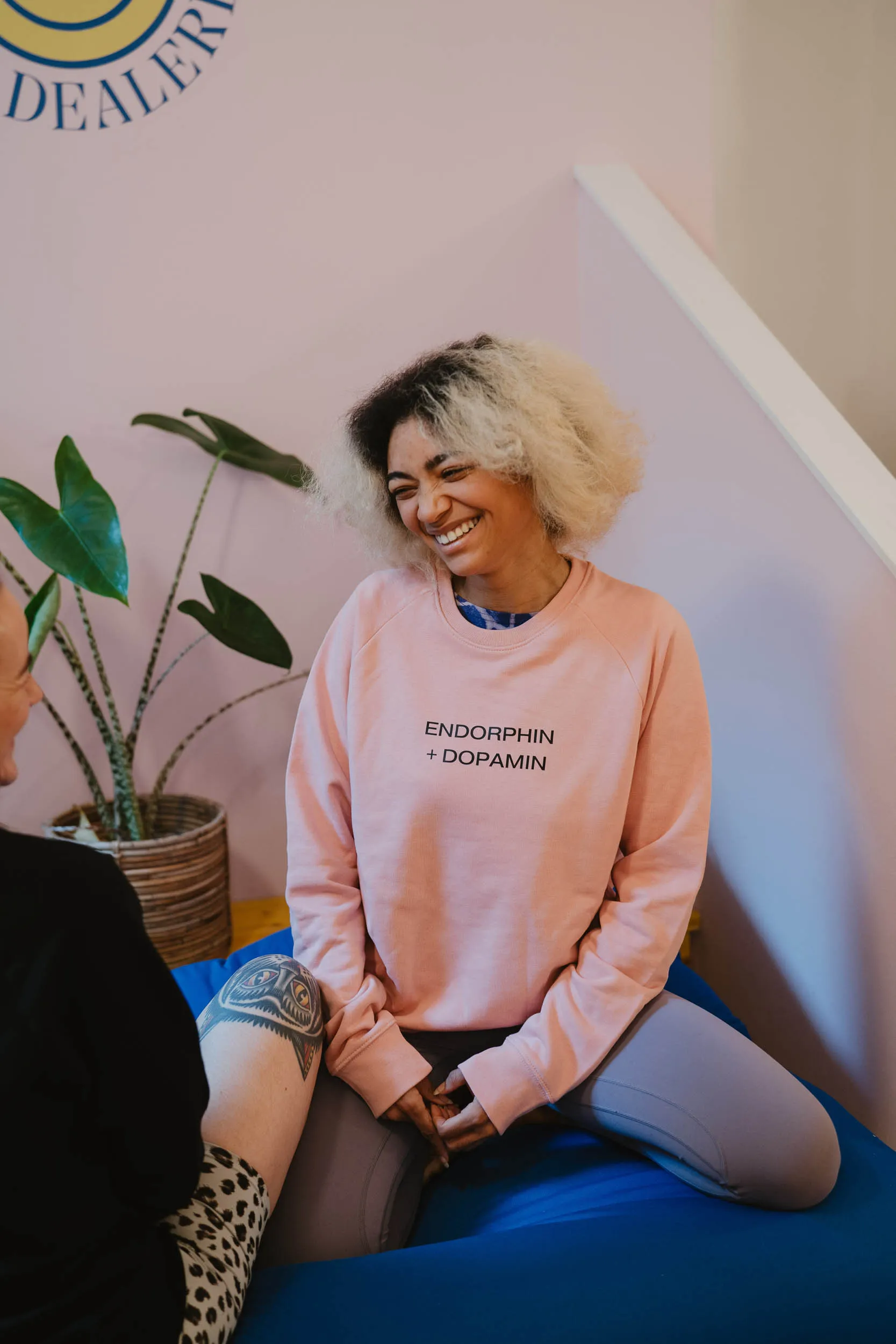 Frau sitzt lachend in Yoga Dealerei