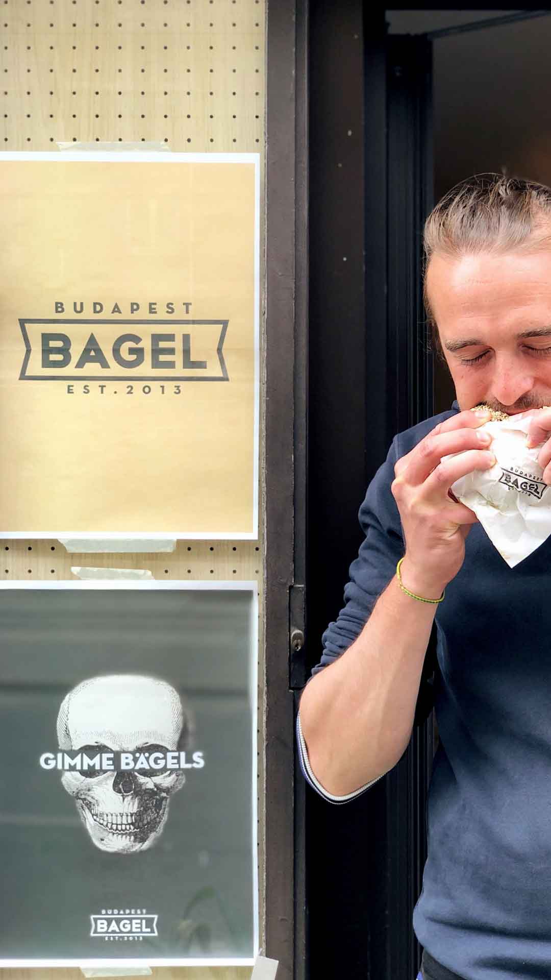Mann beißt in einen Bagel von Budapest Bagel Vienna