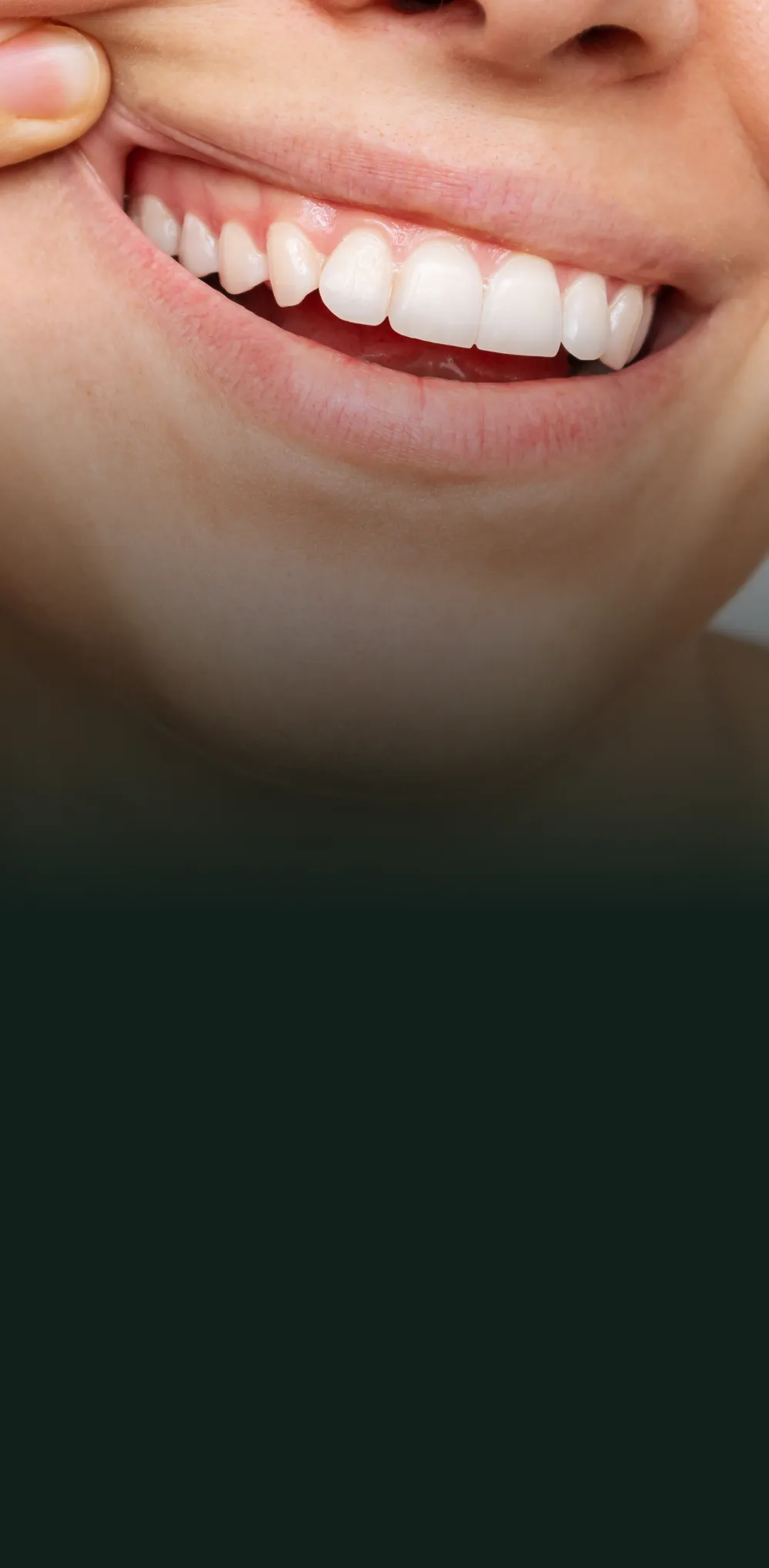 Close-up of a smiling person pulling cheek to show clean, white teeth.