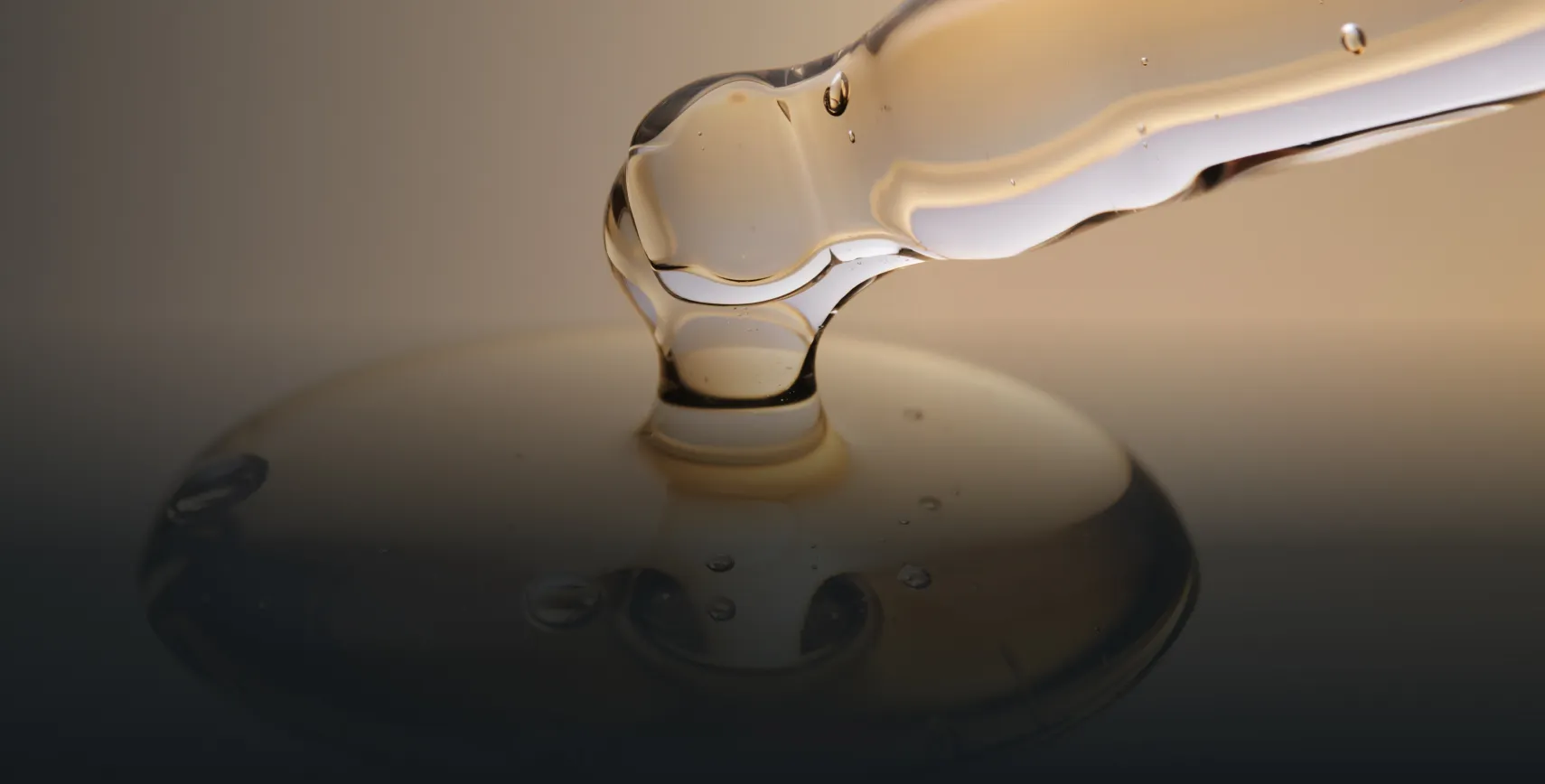 Close-up of clear liquid being dispensed from a dropper onto a surface.