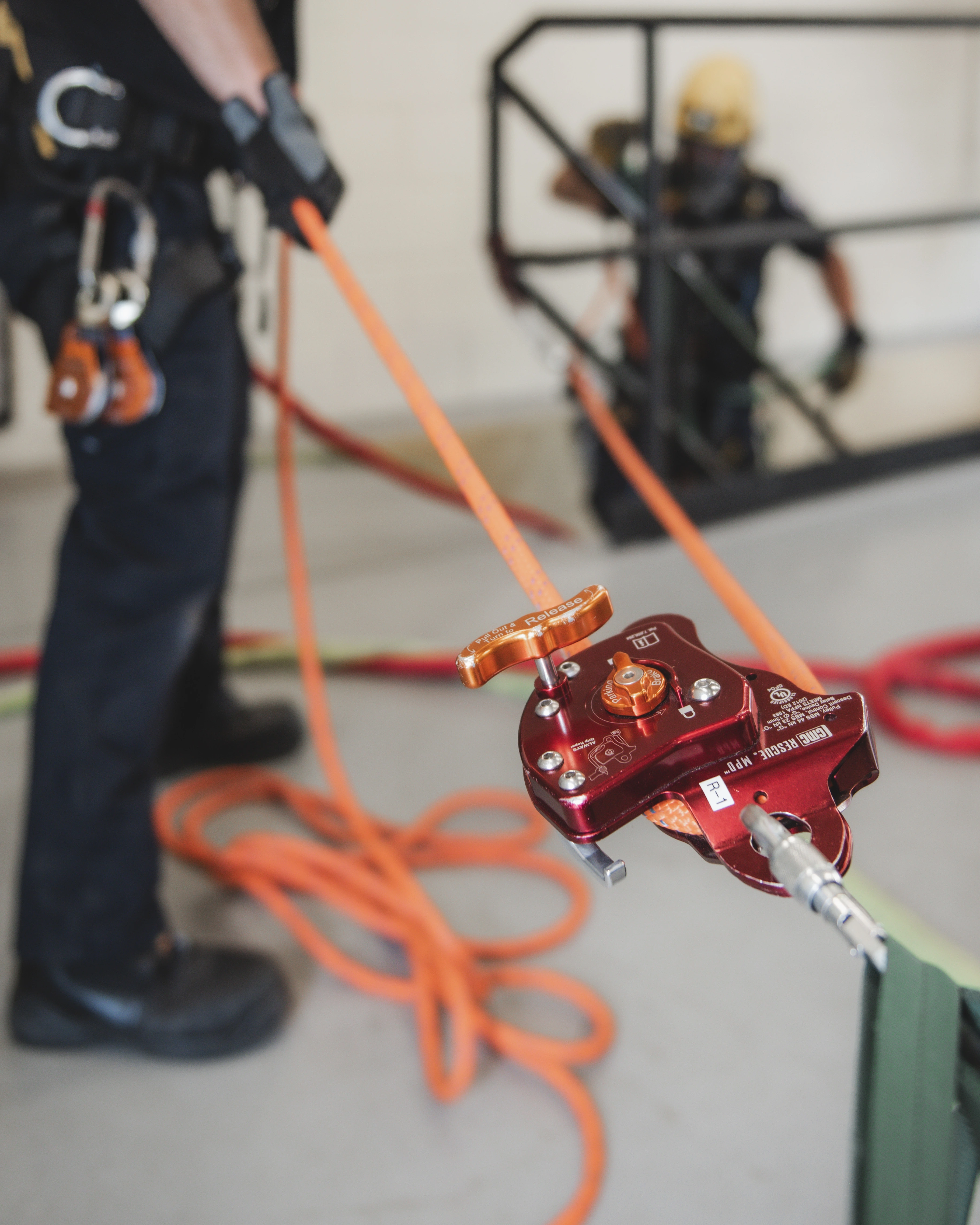 Red CMC rescue pulley device rigged on orange rope during indoor rope rescue training