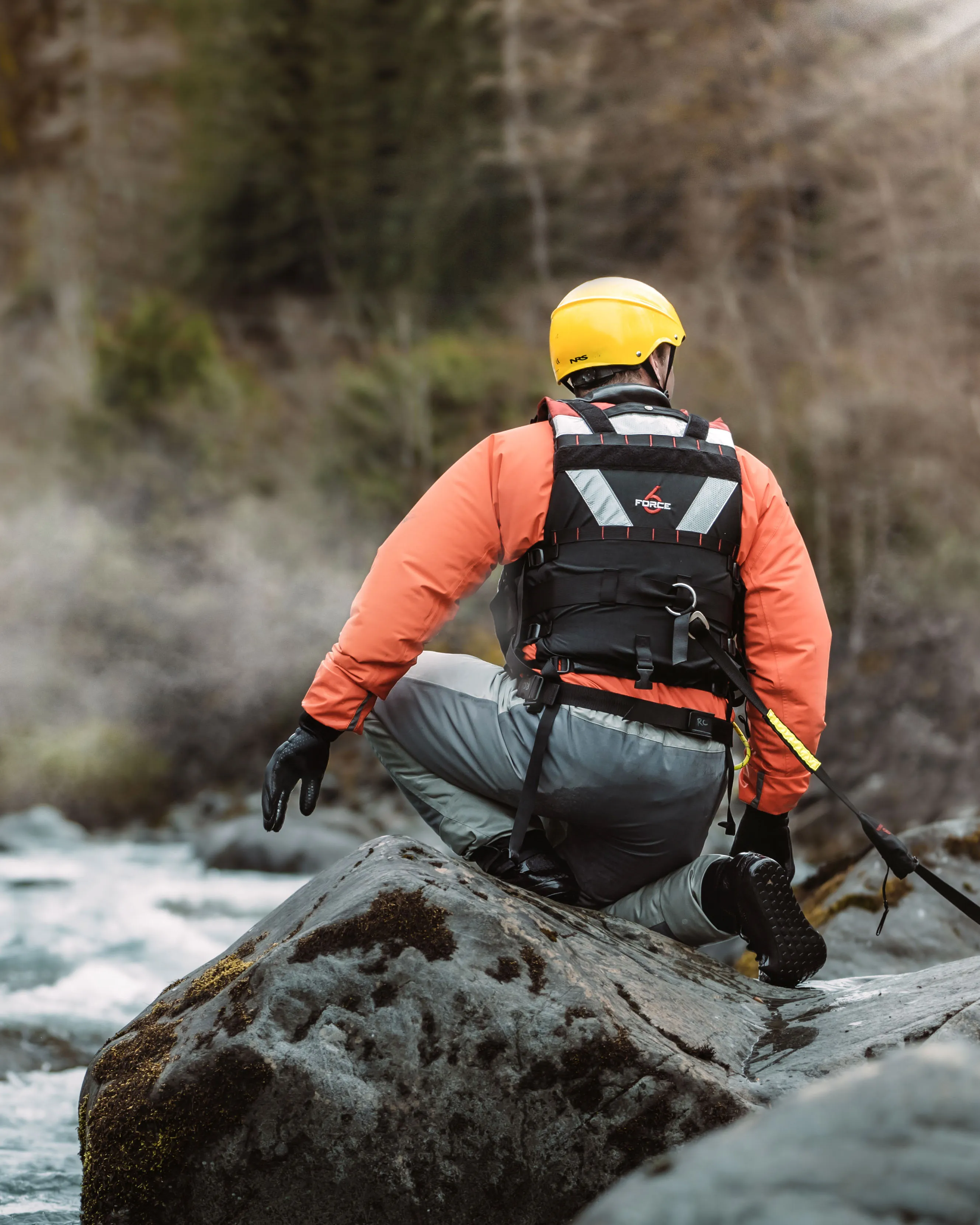 Rescue technician in a red suit and harness walking toward a rescue helicopter