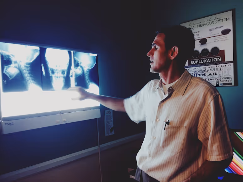 Dr. Keith Lavender reviewing a patient's cervical spine X-rays on a backlit viewer at Foresight Wellness Center