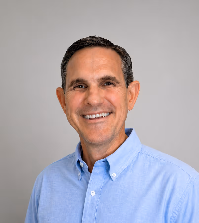 Dr. Keith Lavender wearing a light blue button-up shirt against a gray background.