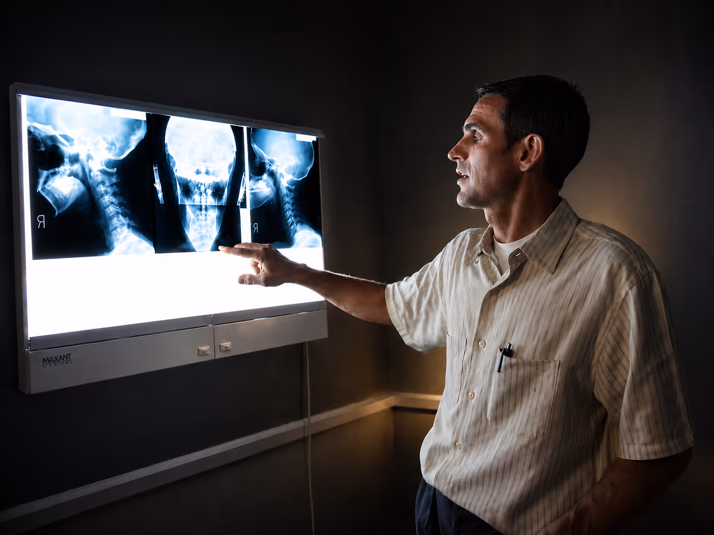 Dr. Keith Lavender reviewing a patient's cervical spine X-rays on a backlit viewer at Foresight Wellness Center