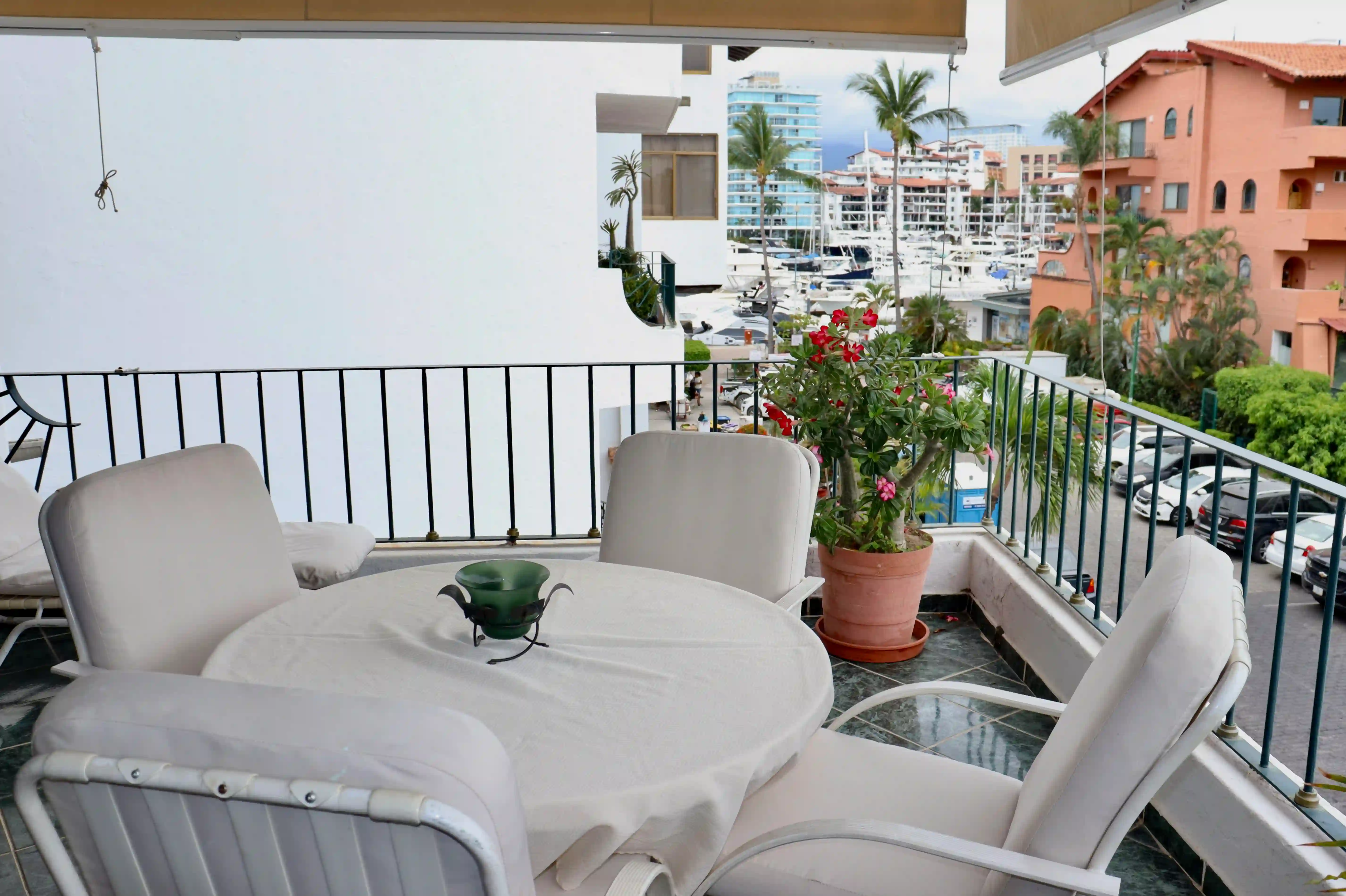 Close-up of the balcony's alfresco dining area with white patio chairs and a round table, perfect for enjoying morning coffee with a view of the Marina Vallarta grounds.