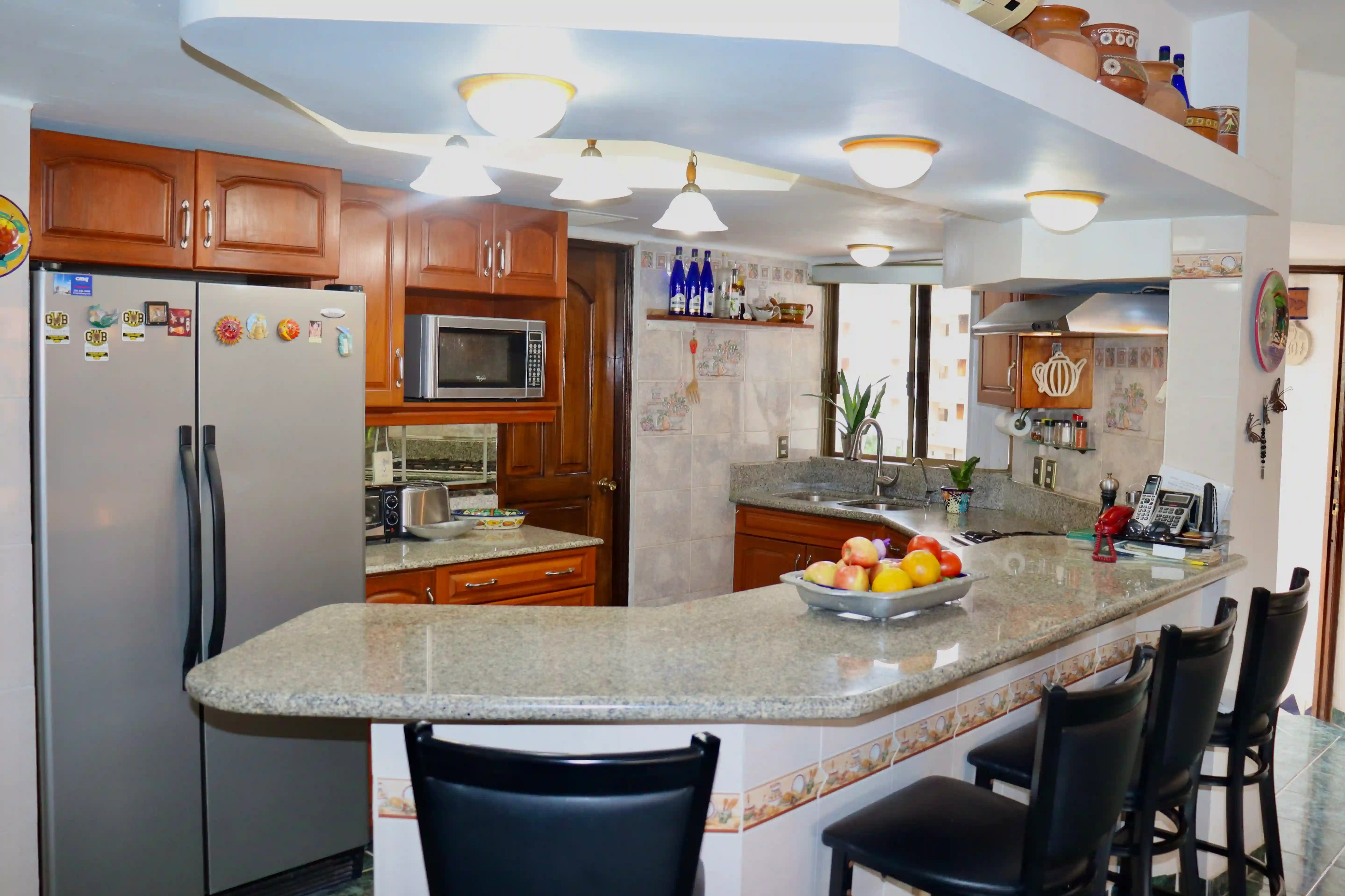 View of the fully equipped kitchen in Royal Pacific 2304, featuring classic wooden cabinetry, a breakfast bar, and integrated appliances.