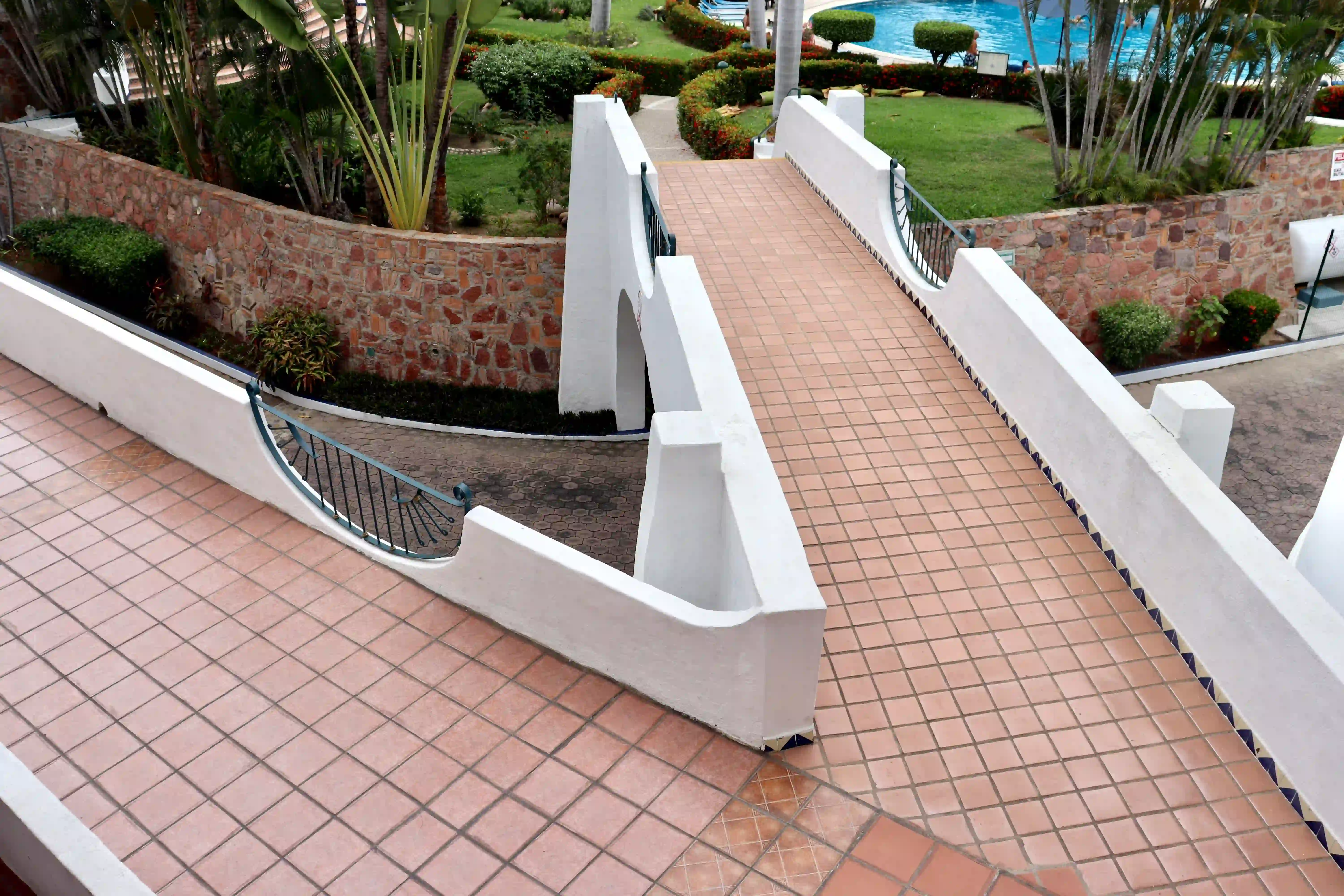 Scenic bridge walkway over the tropical gardens and pool area, showcasing the beautiful architecture and grounds of Royal Pacific.