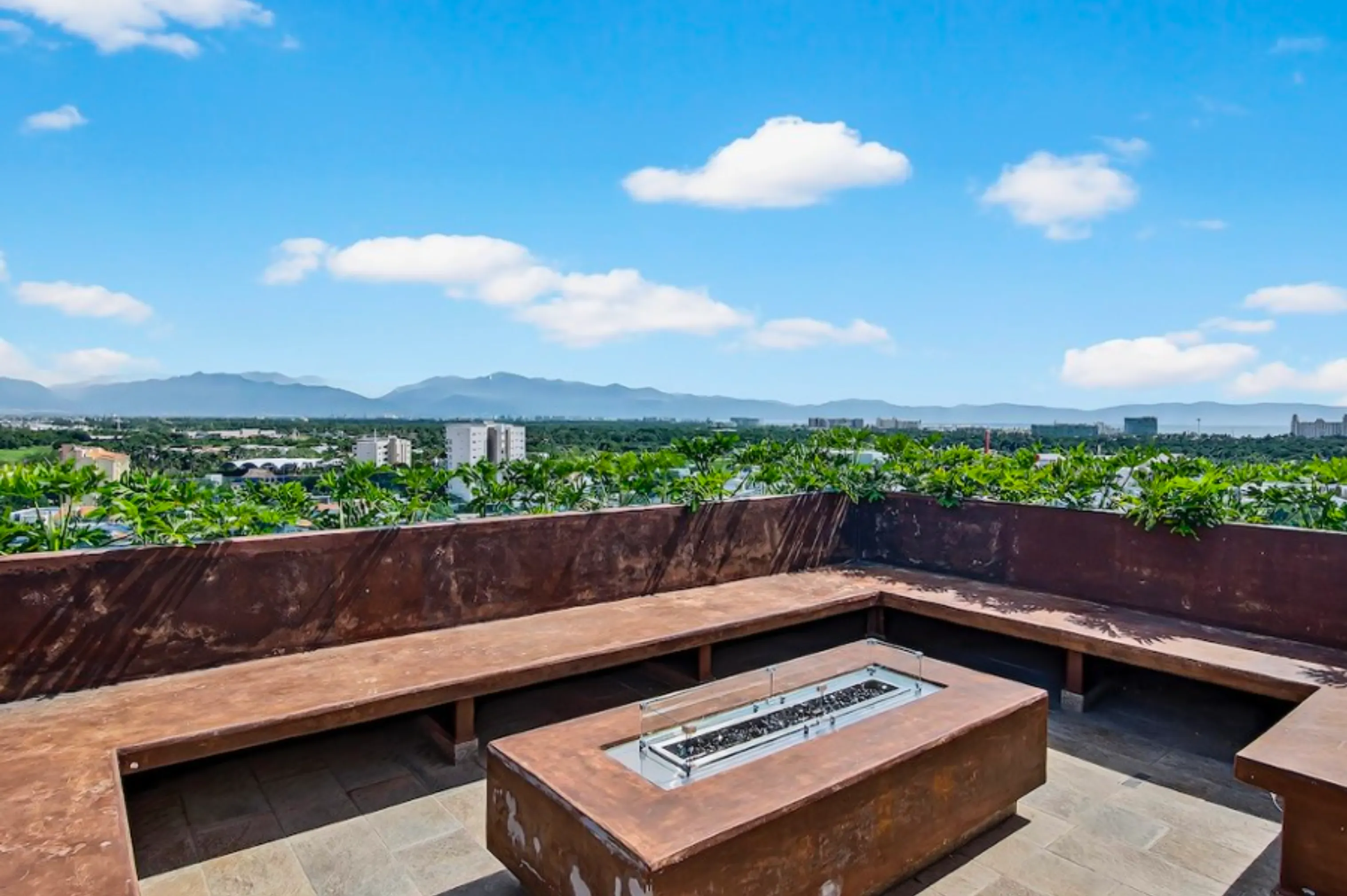 Luxury rooftop lounge area at Believe Flamingos featuring a modern fire pit, comfortable designer outdoor seating, and panoramic sunset views over Nuevo Vallarta.