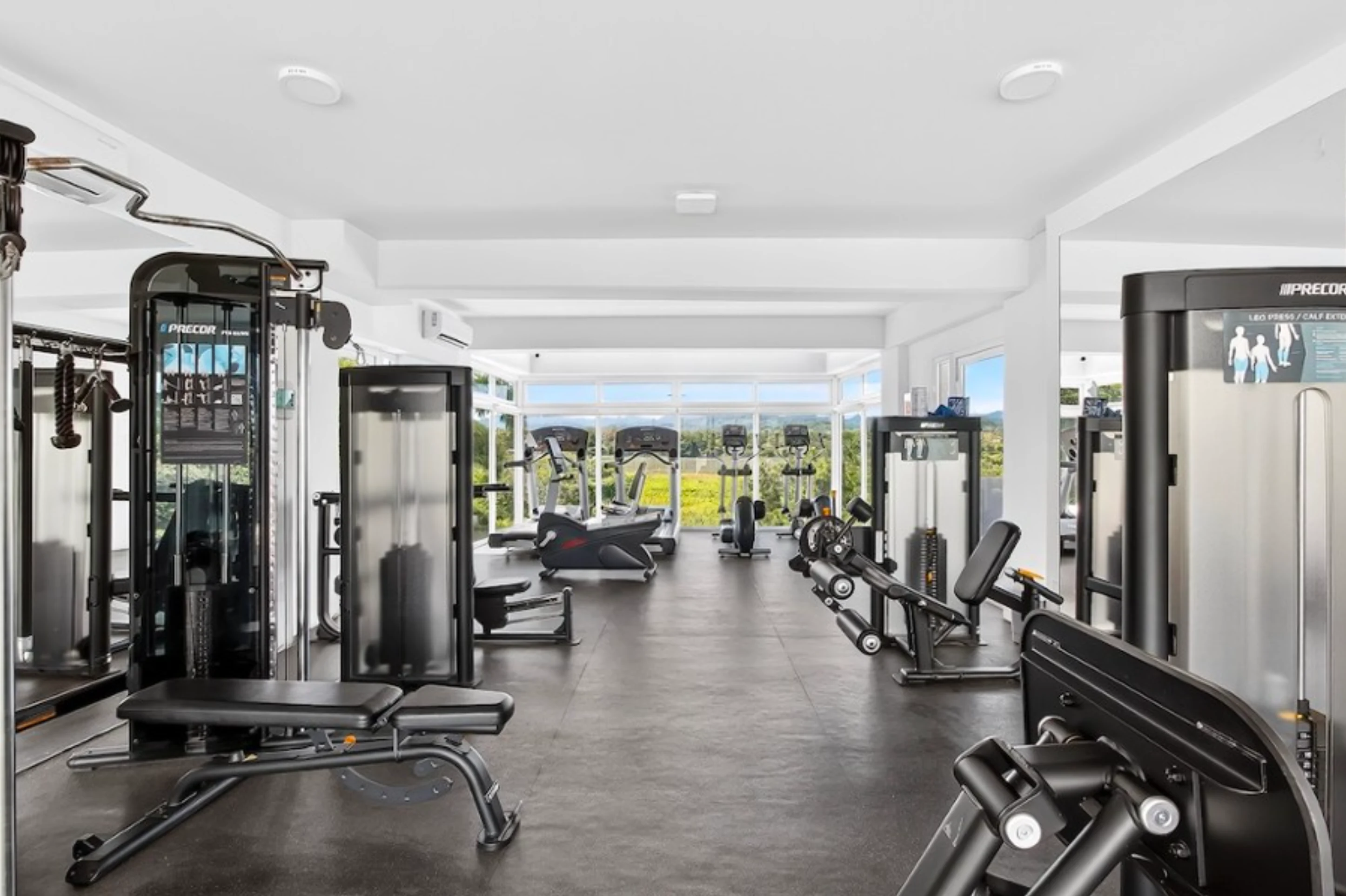 Fully equipped modern fitness center within the Believe development, featuring cardio machines and weight-lifting equipment with a view.