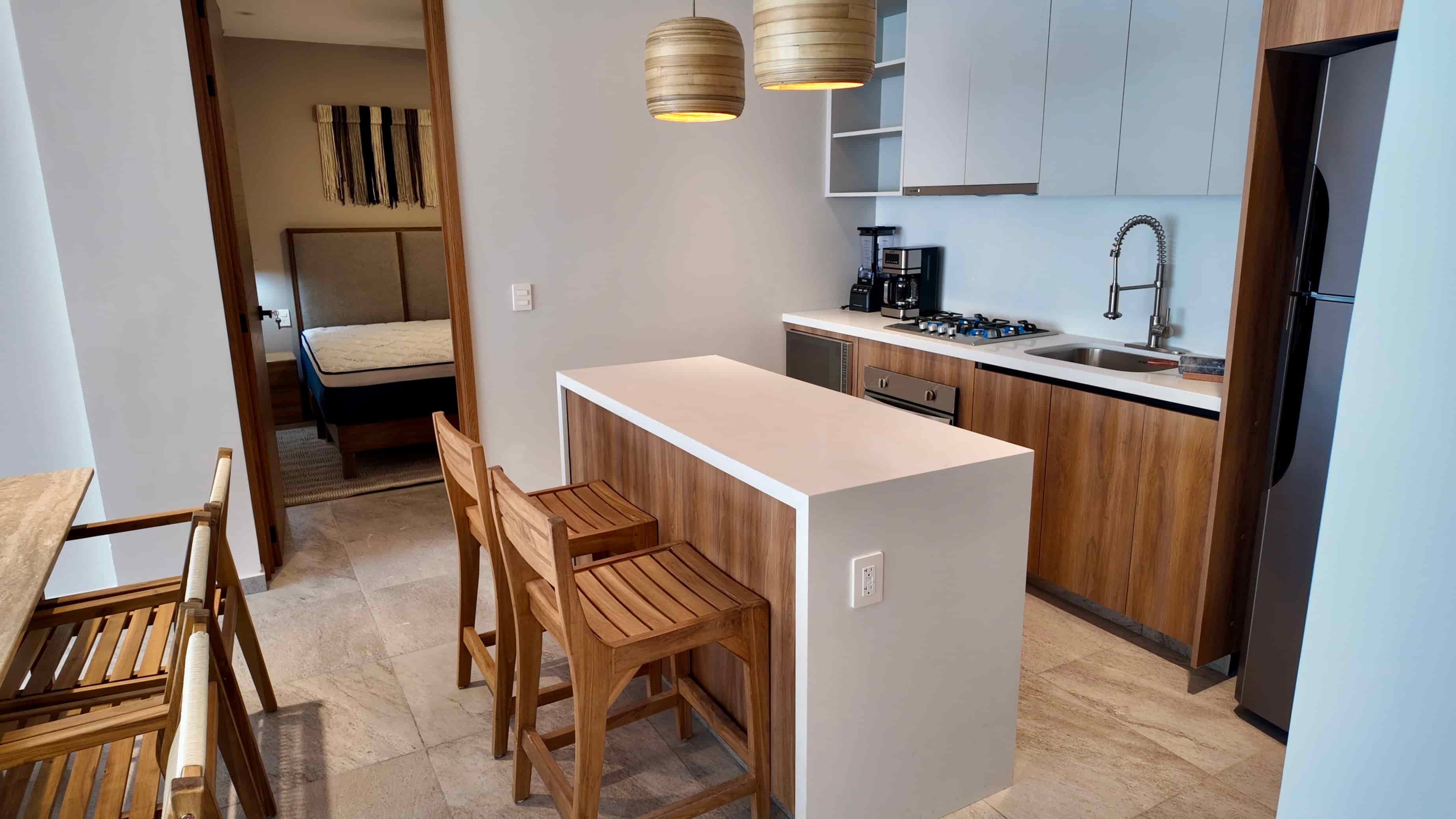 Modern kitchen featuring a breakfast bar with seating, wooden cabinetry, and high-end stainless steel appliances in the TERRA 242 showroom unit.