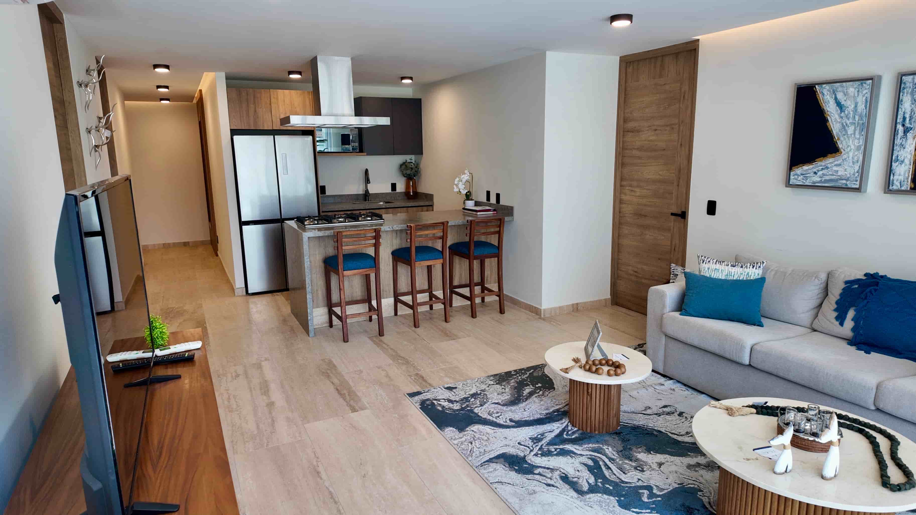 Open-concept living area and kitchen layout featuring sleek tile flooring and modern furniture in the turn-key model unit.