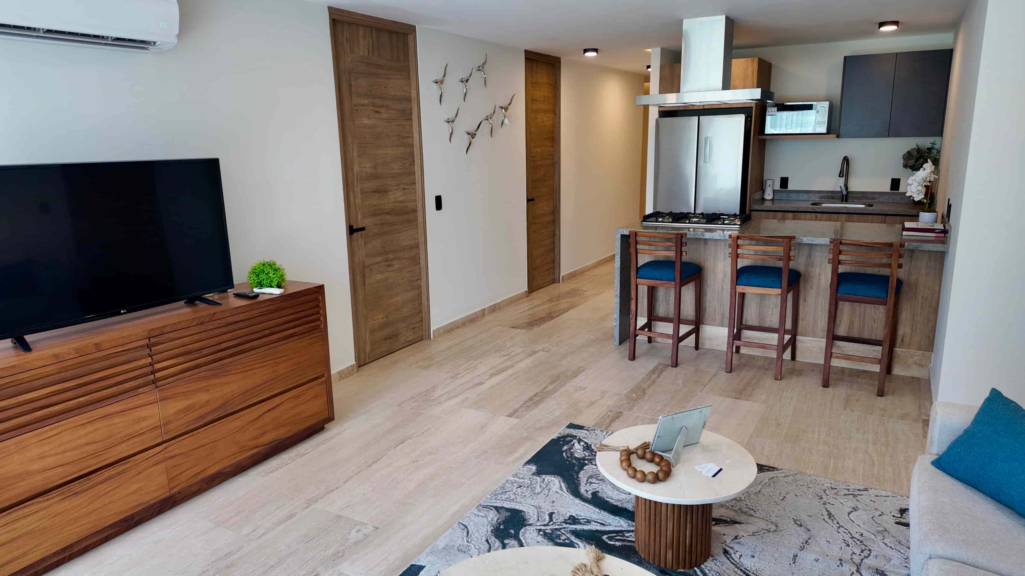 Bright living room connected to an open kitchen with high-end appliances, showcasing a move-in ready luxury condo in Puerto Vallarta.