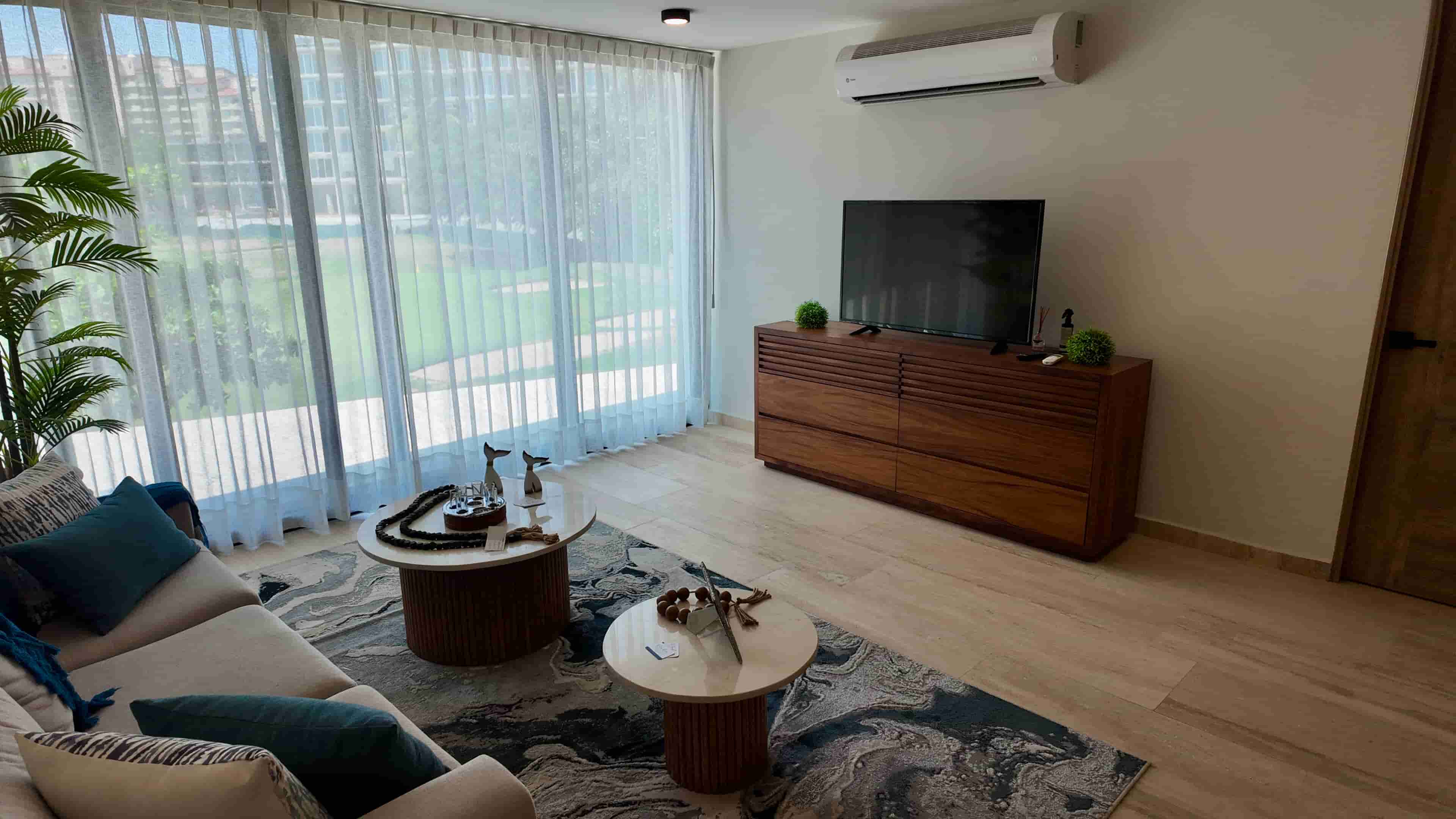 Spacious layout of the main living room looking toward large windows, highlighting the premium interior design of the showroom.