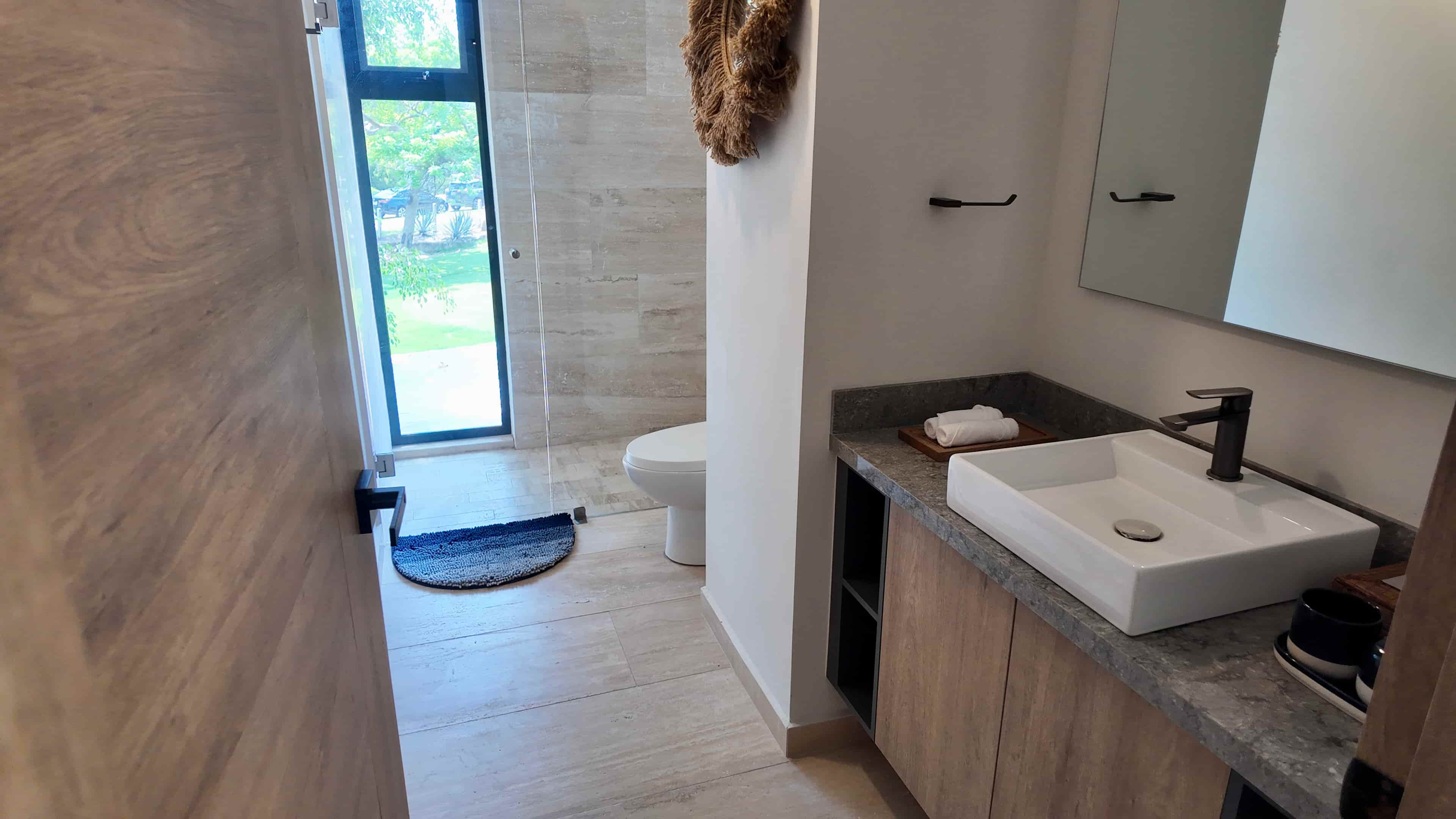 Luxury ensuite bathroom with a sleek glass shower enclosure, contemporary floating vanity, and marble-look tiling.