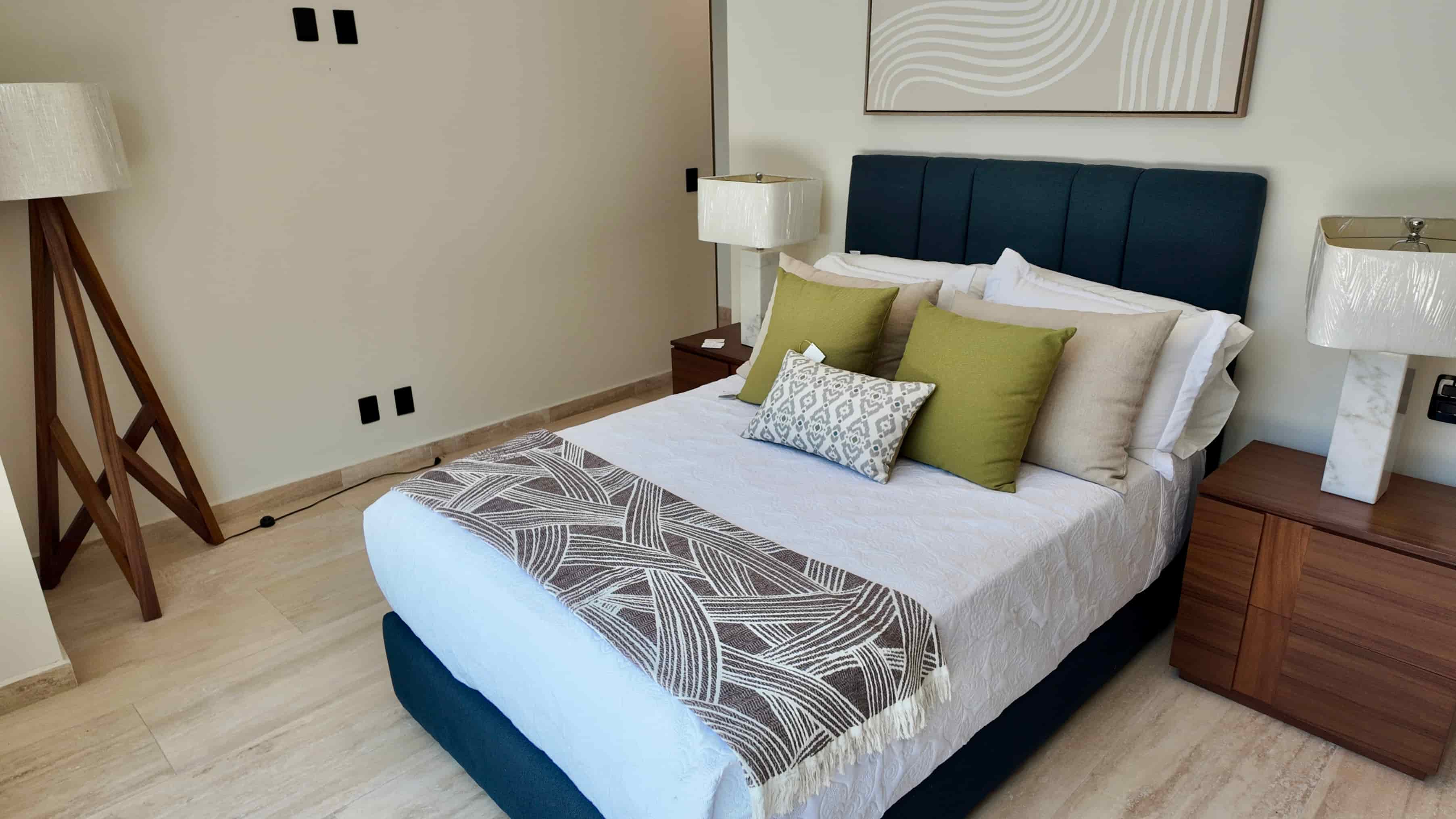 Beautifully staged master bedroom in the Batros showroom, showcasing high-end linens, decorative accent walls, and side tables.