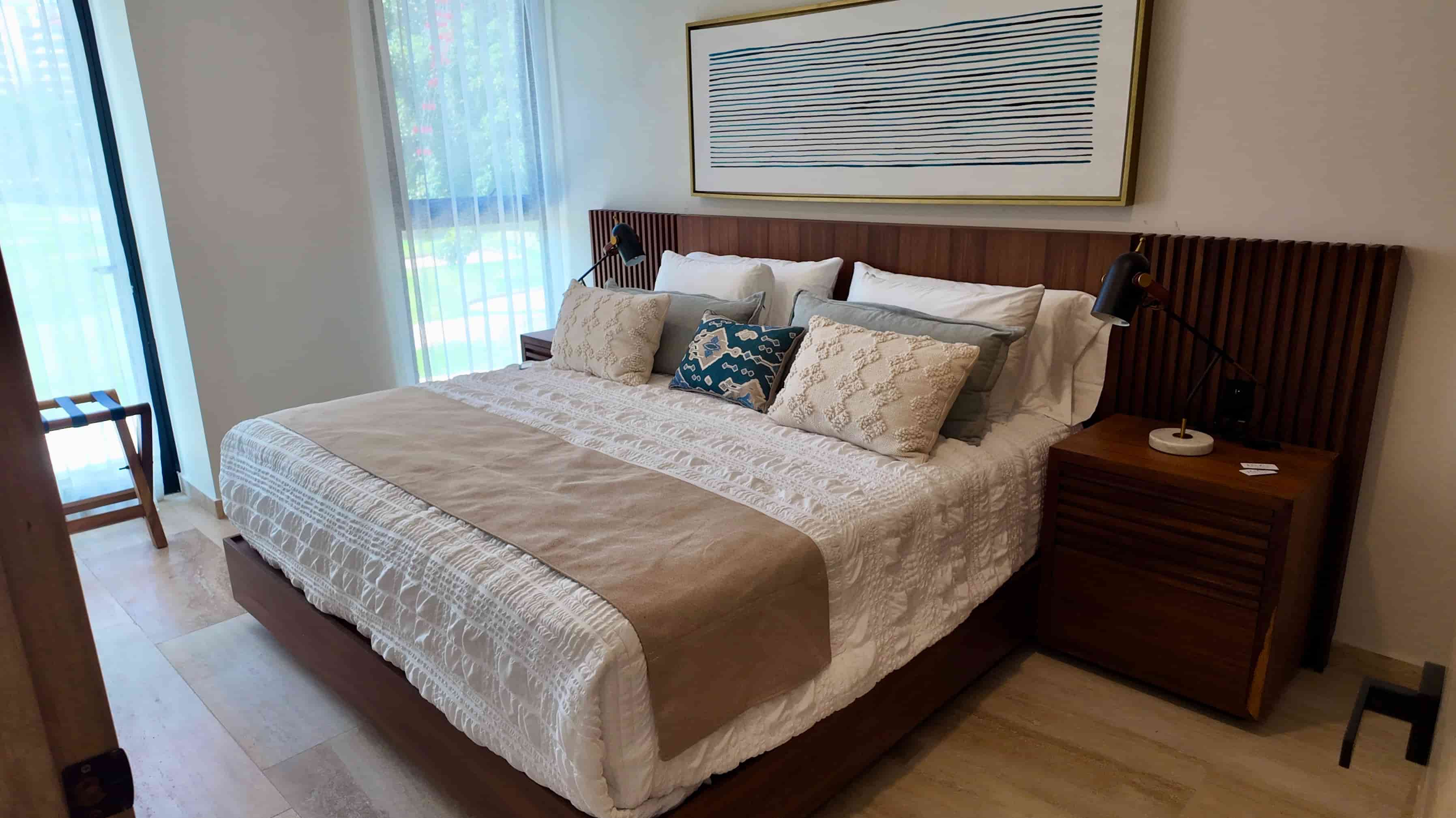 An alternative view of the luxury master suite bedroom, highlighting a large wooden headboard, elegant decor, and bright natural lighting.