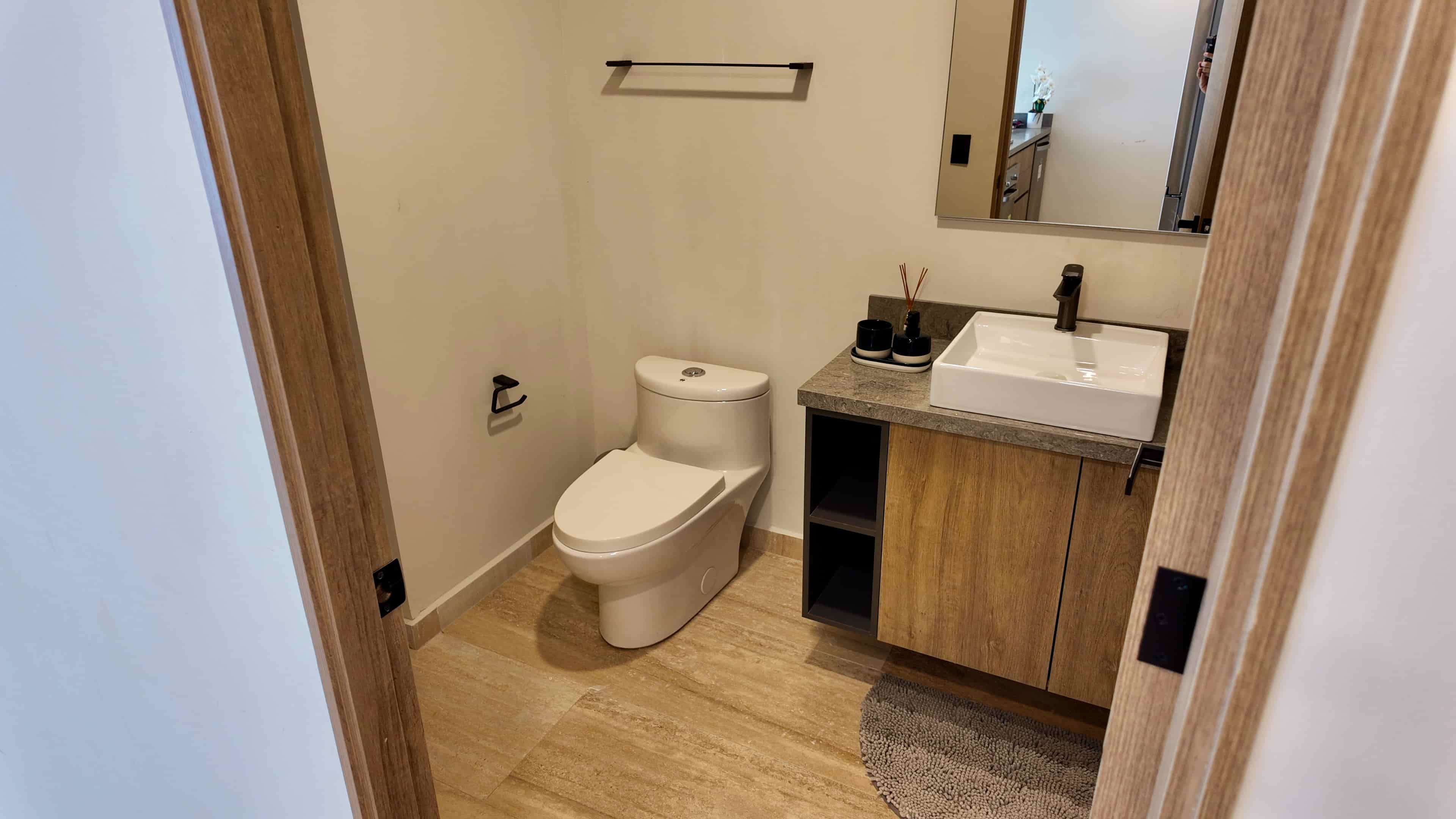 Minimalist powder room design with a porcelain vessel sink, warm wood details, and premium chrome fixtures.