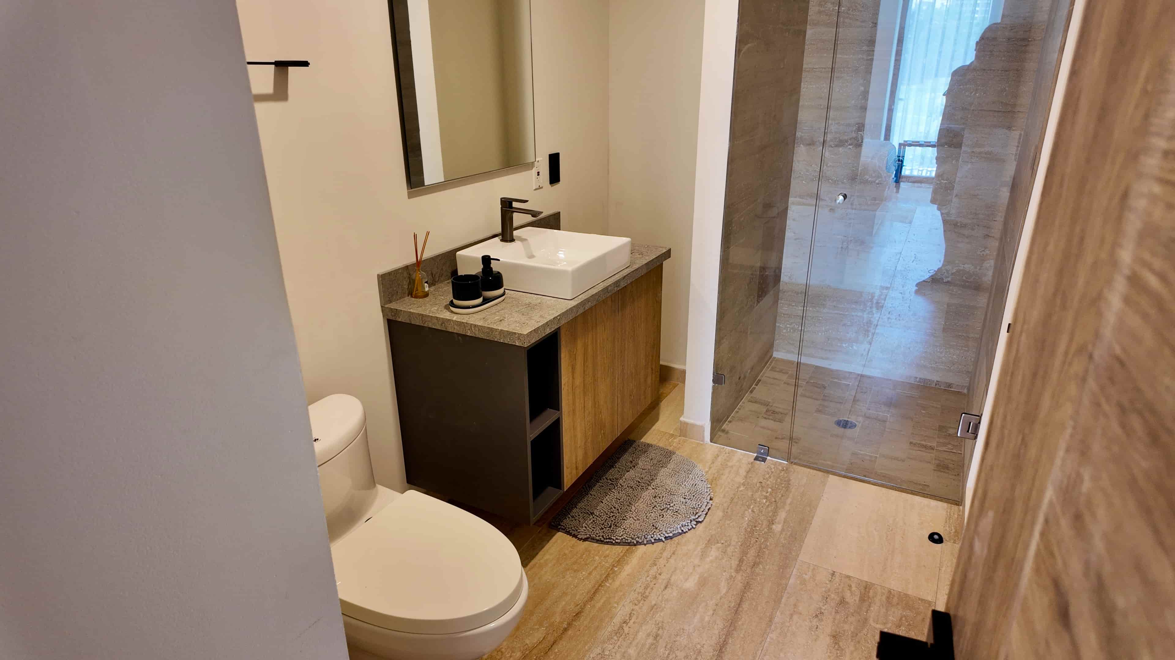 Elegant vanity space with built-in wooden drawers, strategic LED ambient lighting, and a large mirror in the model unit bathroom.