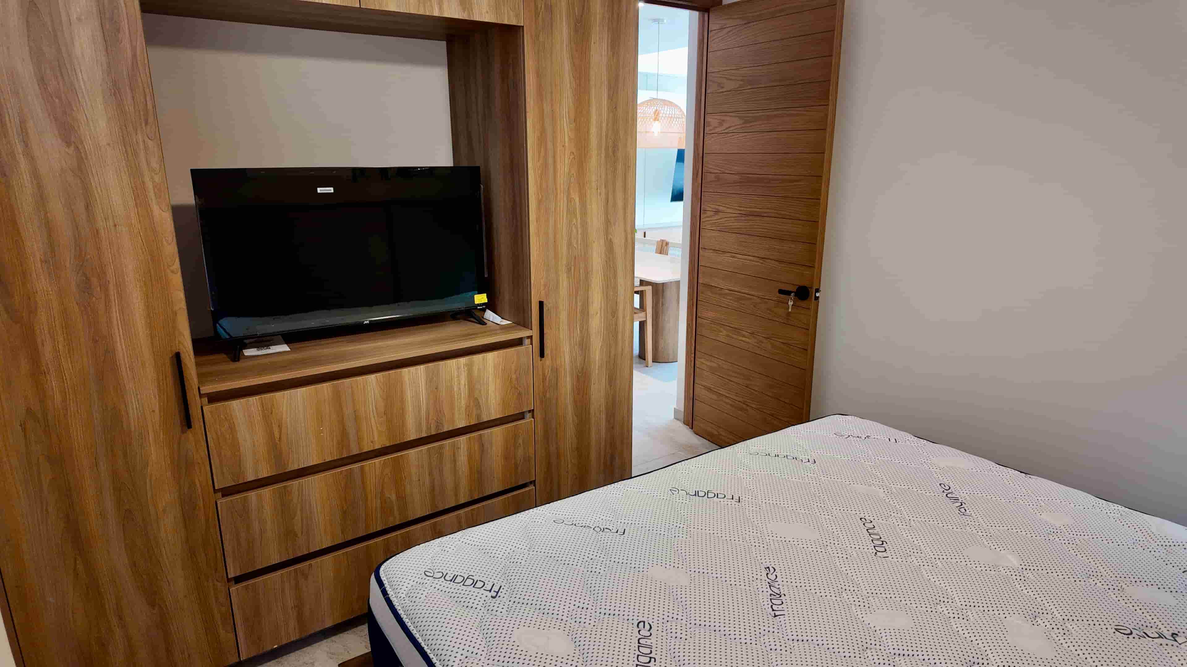Compact bedroom setup with an integrated entertainment center and wooden finishes, maximizing floor space in TERRA 242.