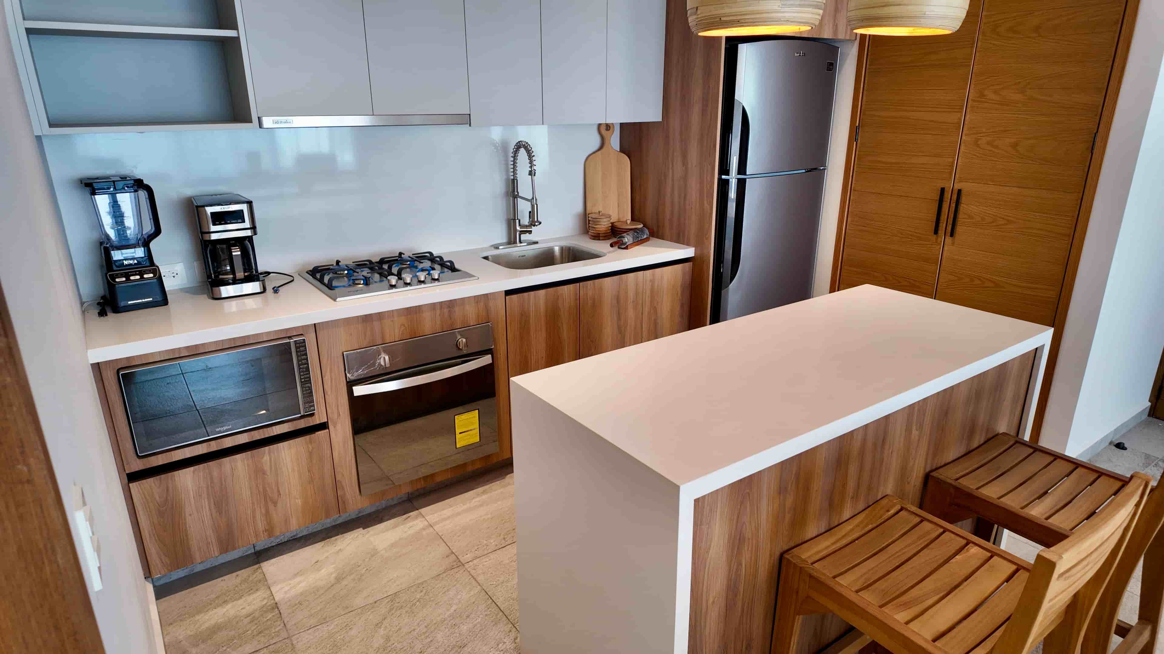 Detailed shot of the modern TERRA 242 kitchen layout, featuring compact island seating, integrated stove, and premium wooden cabinets.