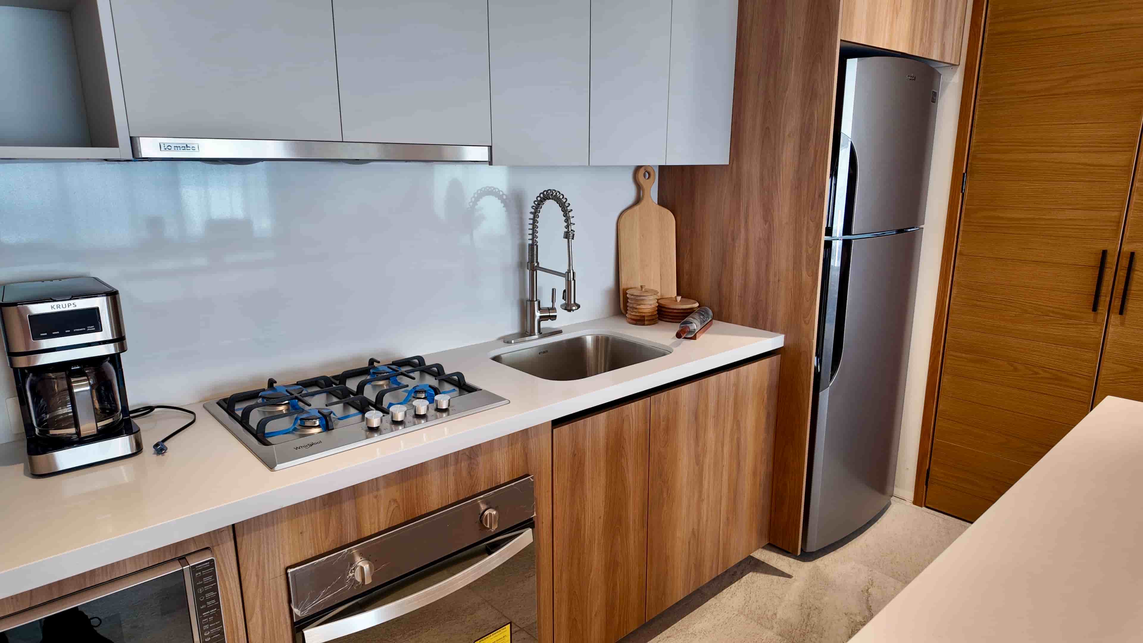 Close-up of the TERRA 242 kitchen workspace with stainless steel sink, gas stovetop, tile backsplash, and built-in refrigerator.