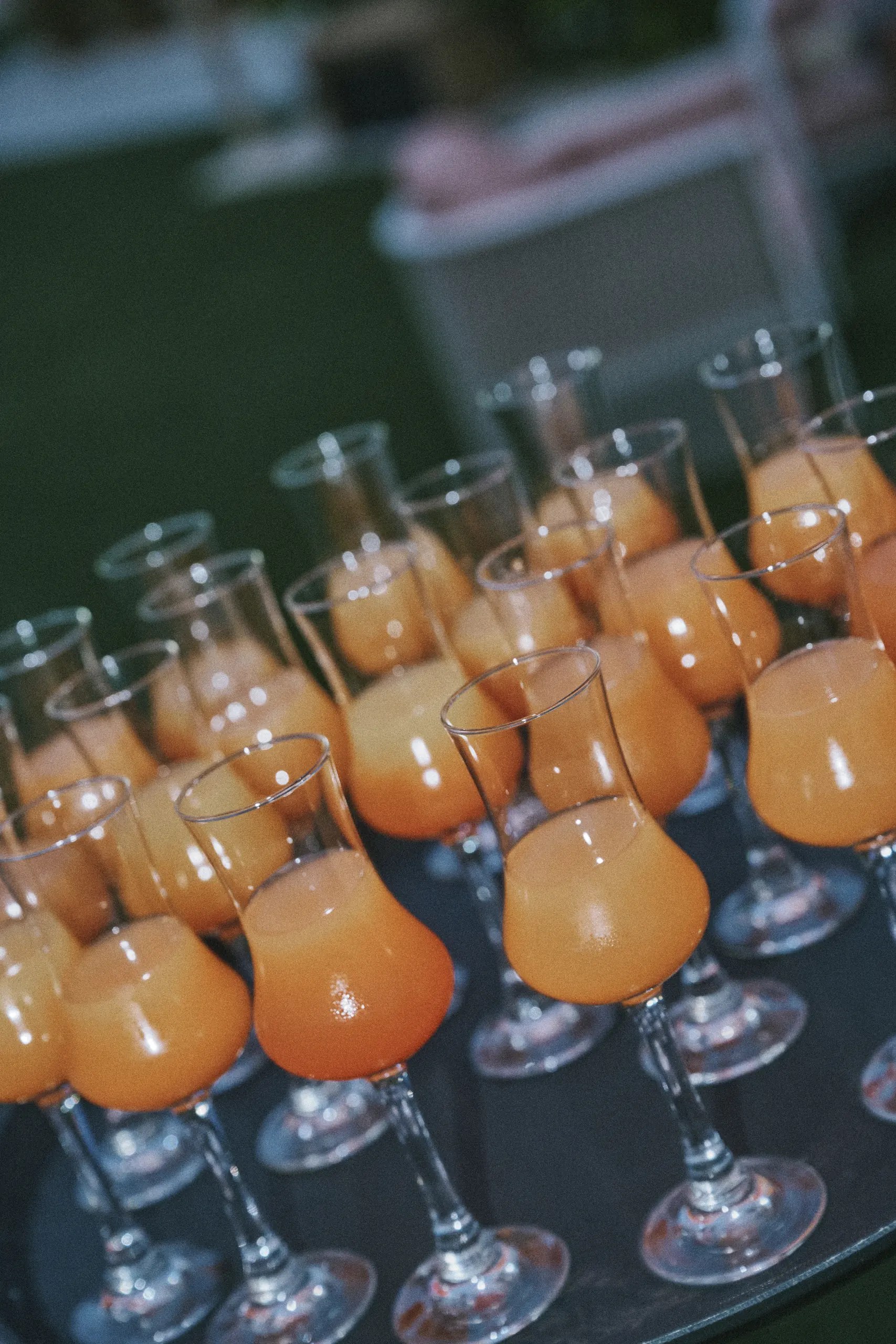 Multiple glasses filled with an orange-colored beverage placed on a dark surface.