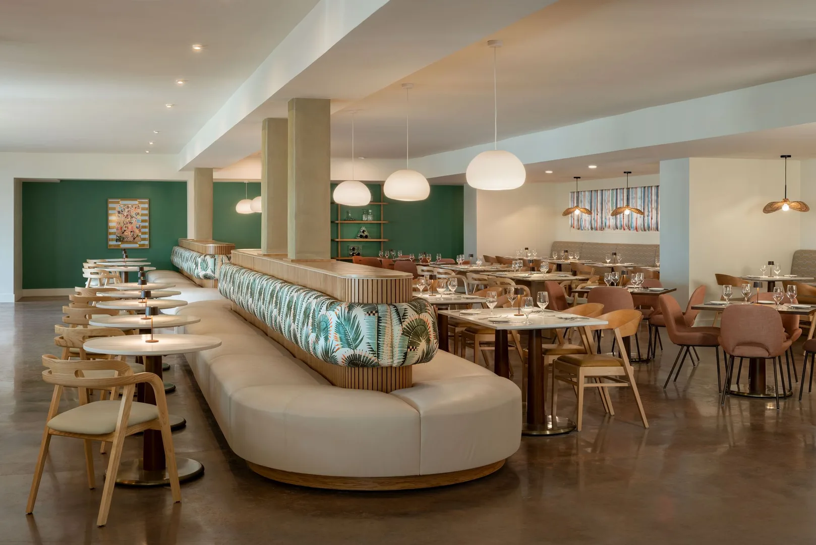 Sundrop dining room with a curved banquette, wooden chairs, and tables set beneath white pendant lights.
