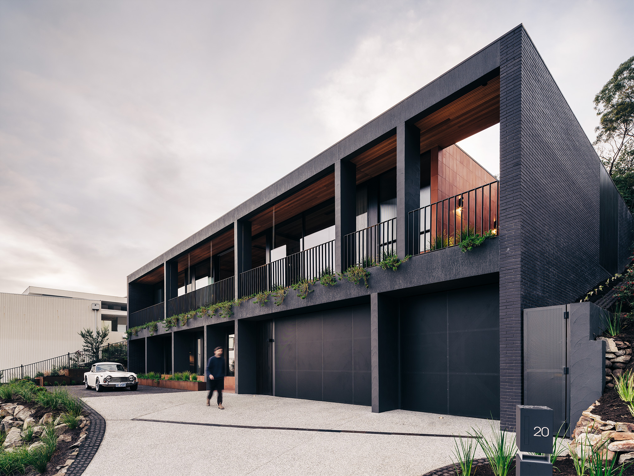 large two storey rectangular home nestled into hilltop