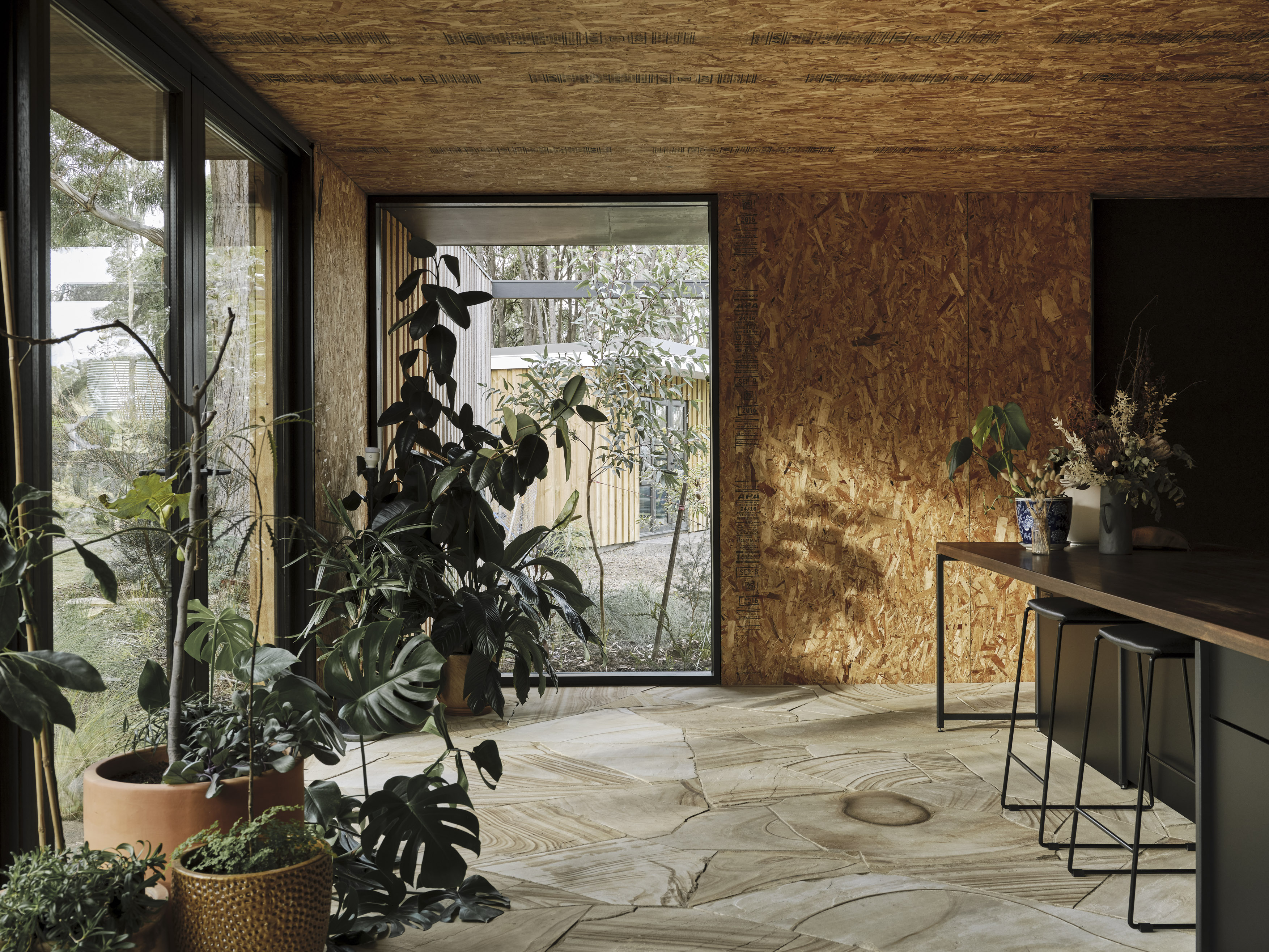 exposed raw timber OSB ceiling with sandstone floor