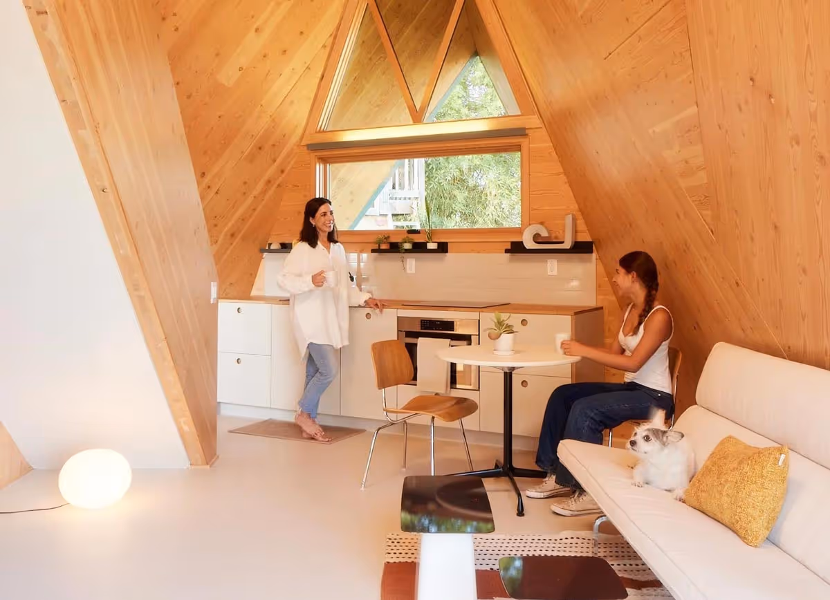 Bright interior of the Tetra with exposed wood A-frame ceiling and two people relaxing inside