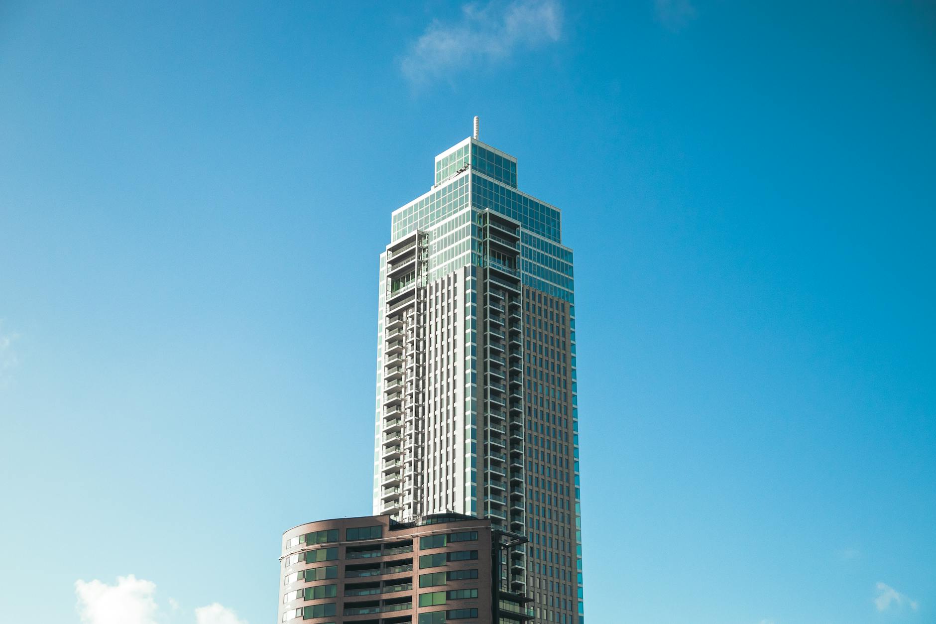 Detailed view of a modern skyscraper in Rotterdam under a clear blue sky.