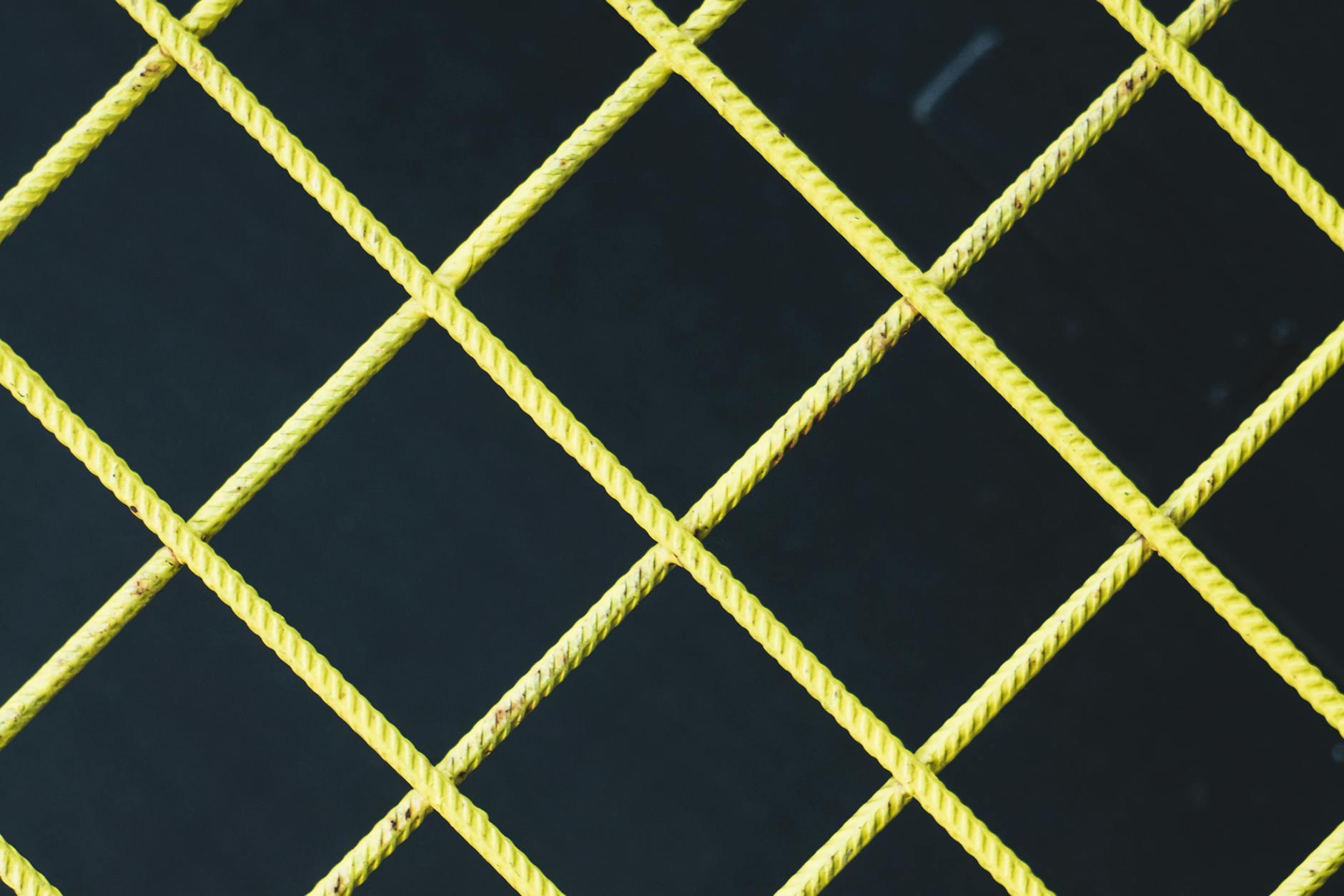 Detailed shot of a yellow crossbar fence against a black background, Oslo, Norway.