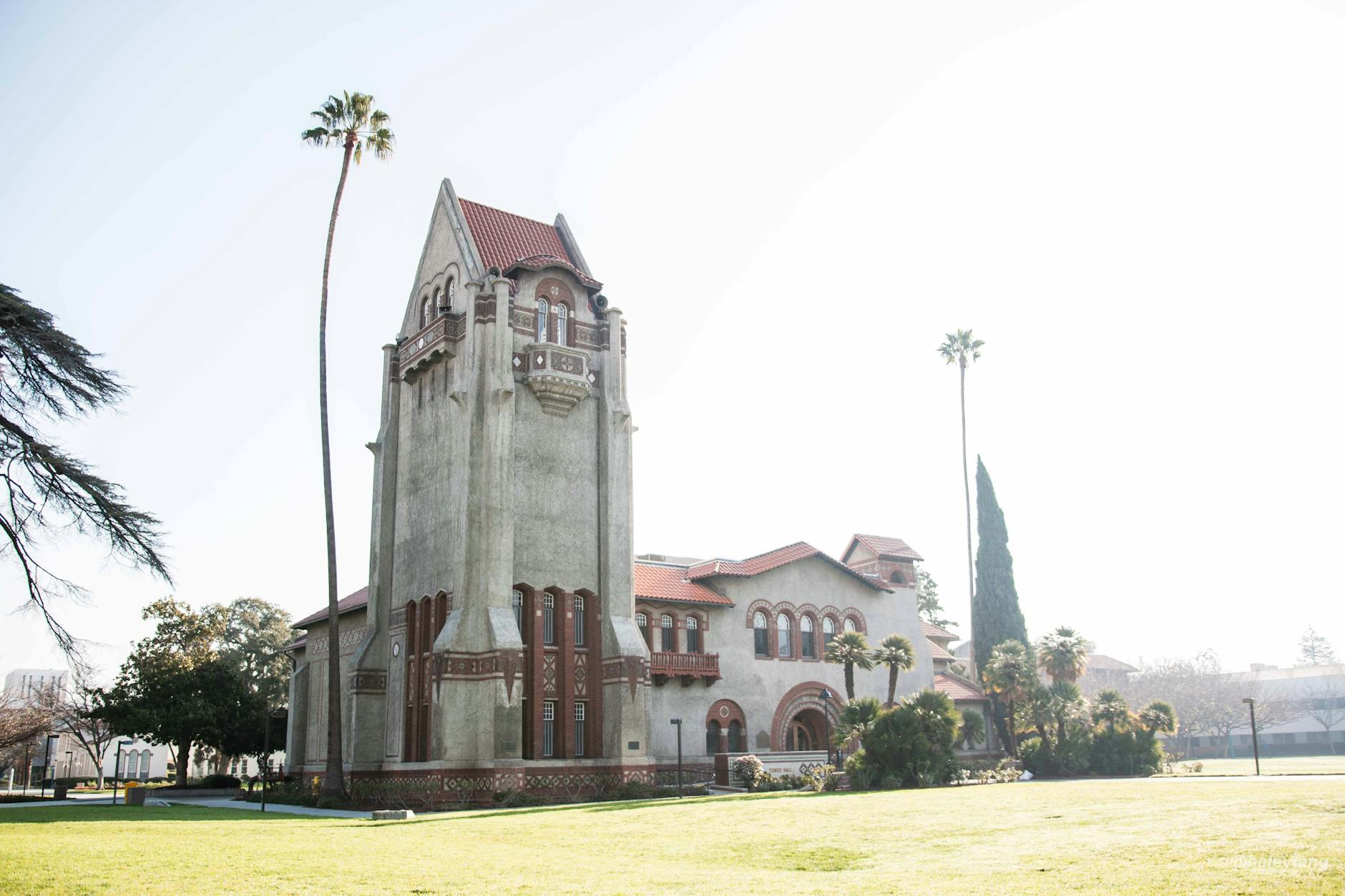 Tower Hall at San Jose State University amid palm trees under a bright summer sky.