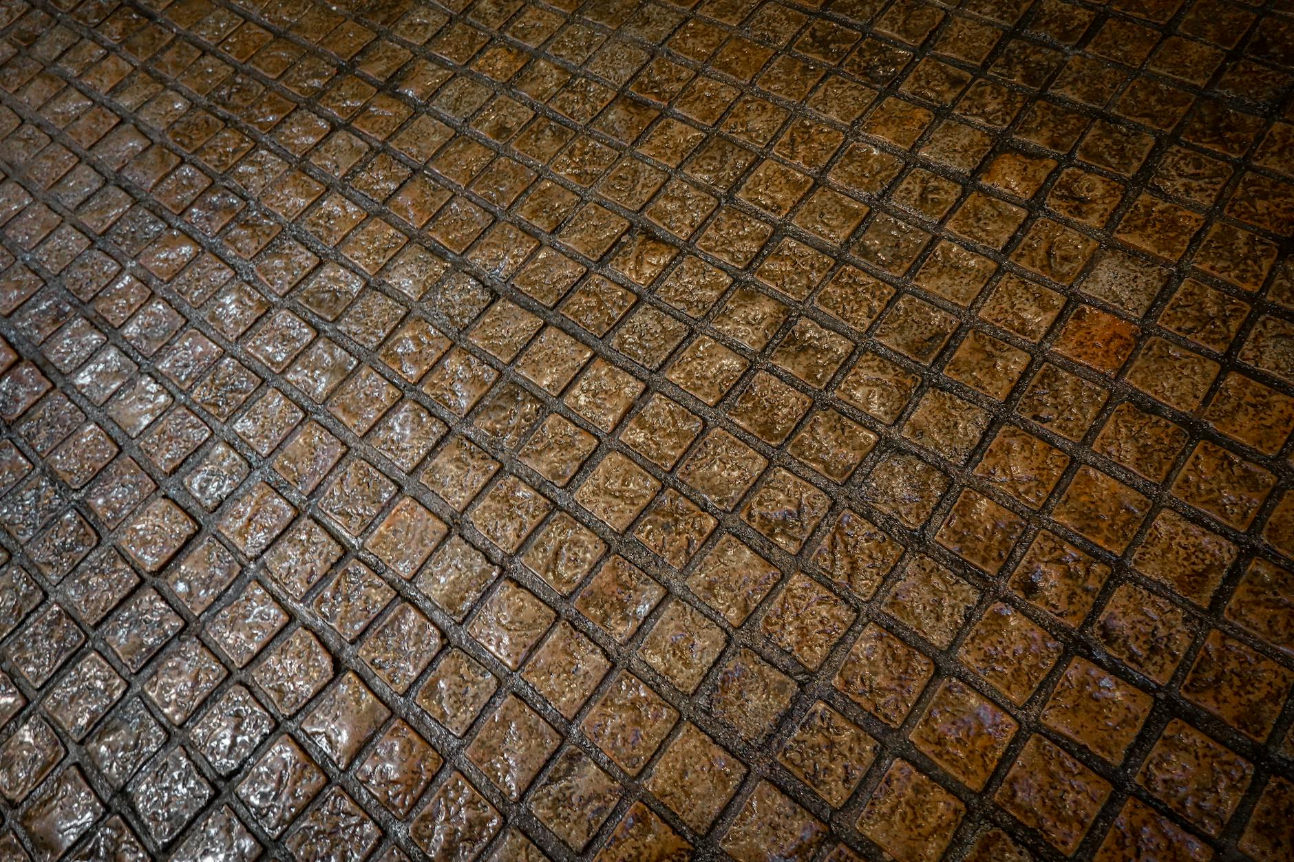 Textured wet cobblestone sidewalk showcasing intricate patterns and rich colors.