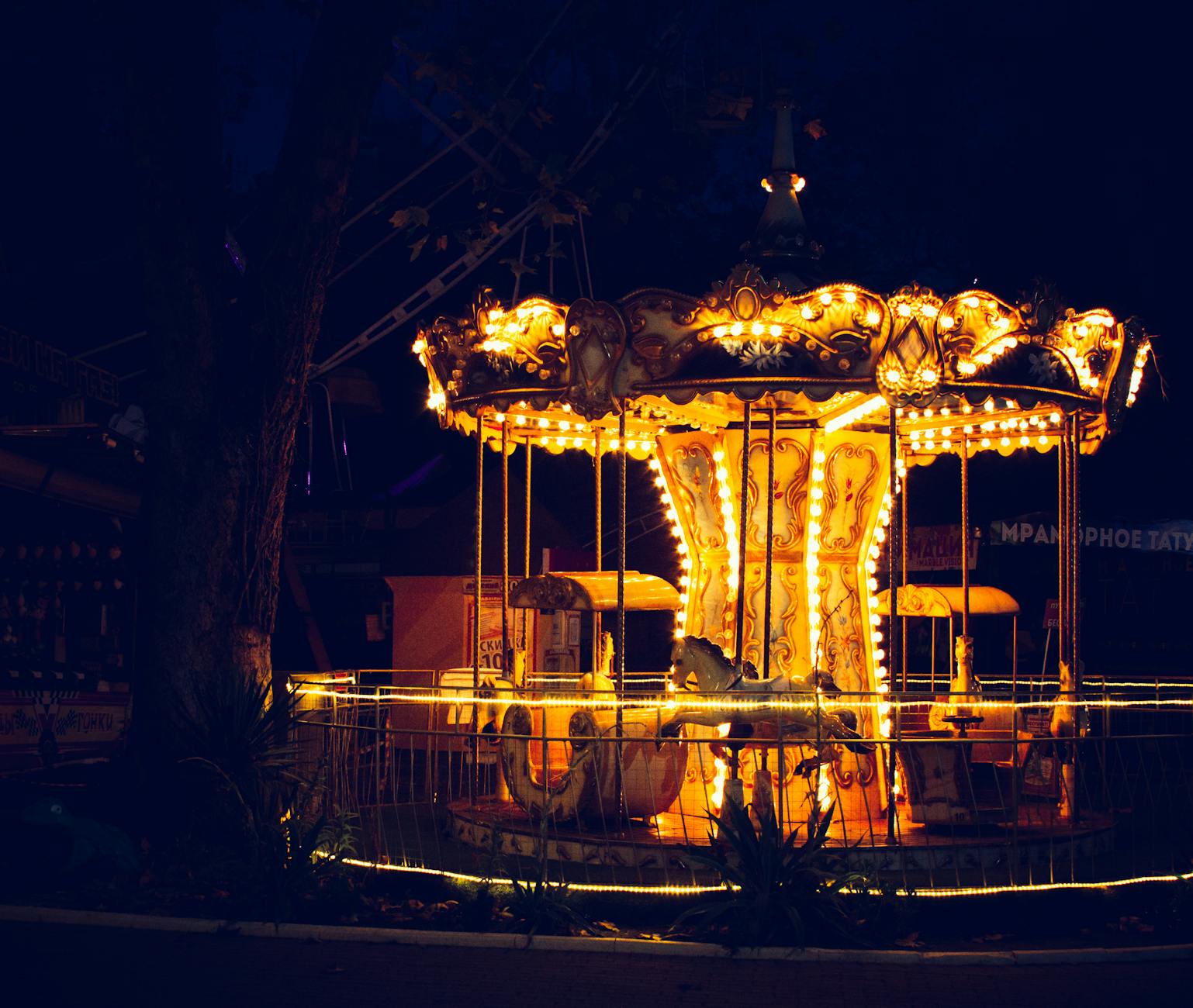 An enchanting view of a brightly lit carousel in a theme park at night.