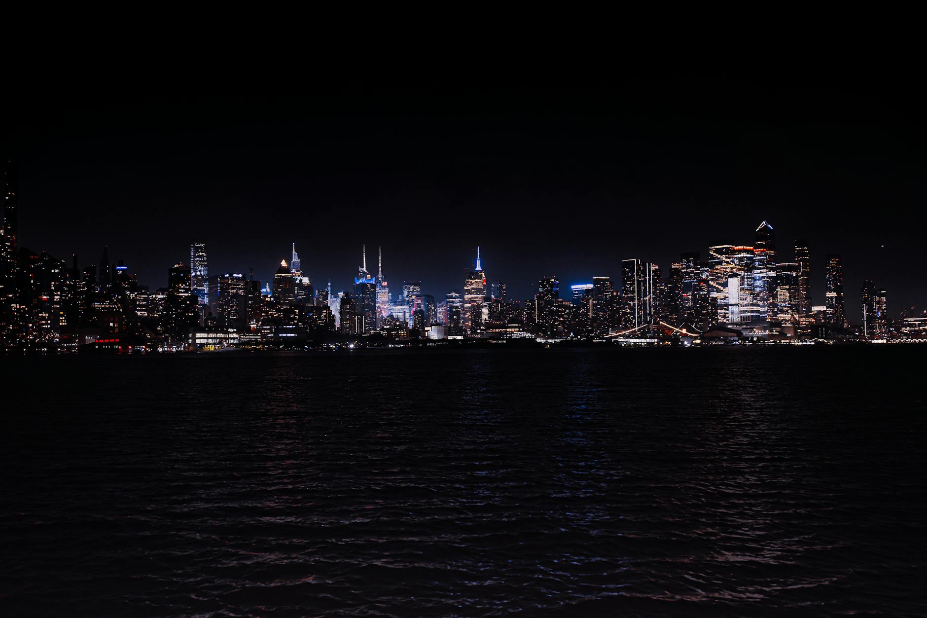 Breathtaking night view of the illuminated New York City skyline across the water.