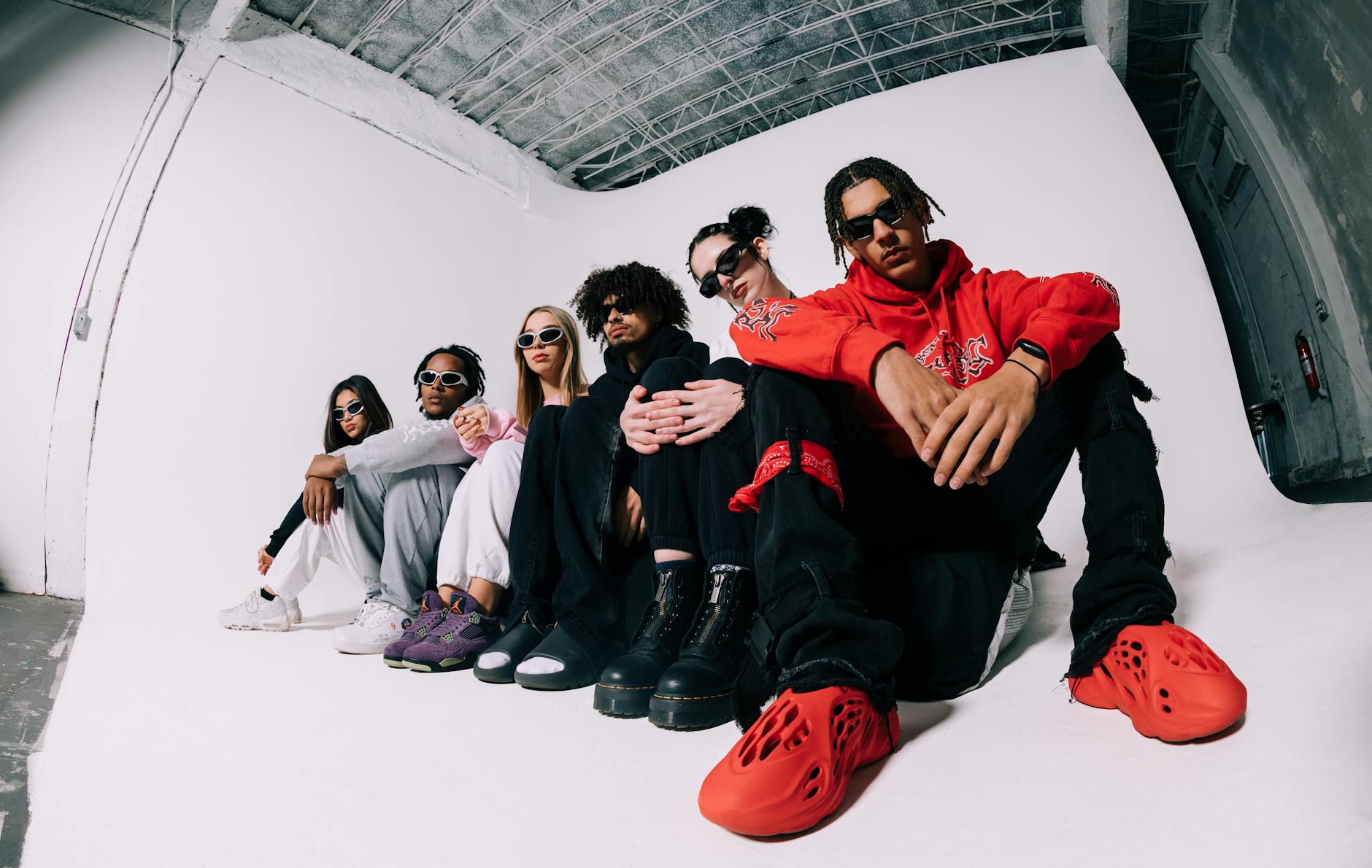 Trendy young adults posing together in fashionable outfits and sunglasses in an urban setting.