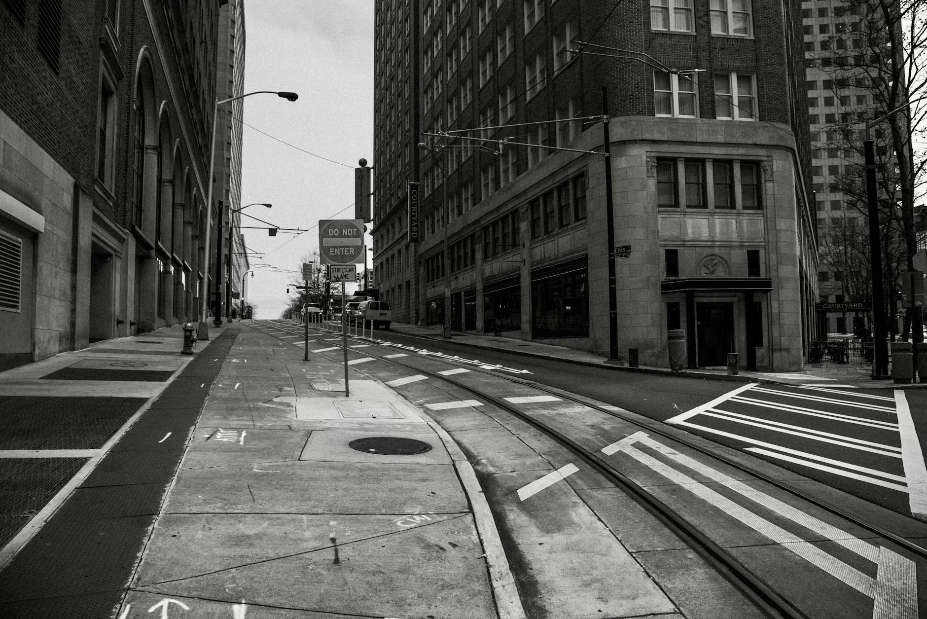 Black and white city street view with tram lines and skyscrapers.