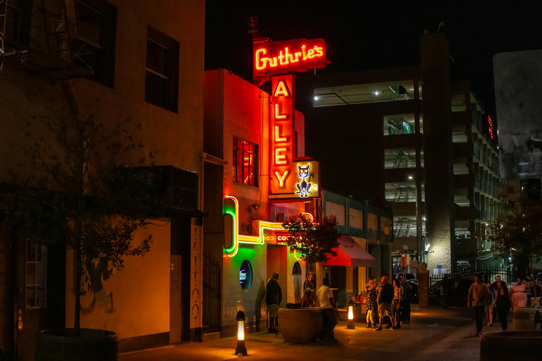Vibrant night street scene with neon signs at Bakerville's Guthrie's Alley Cat.