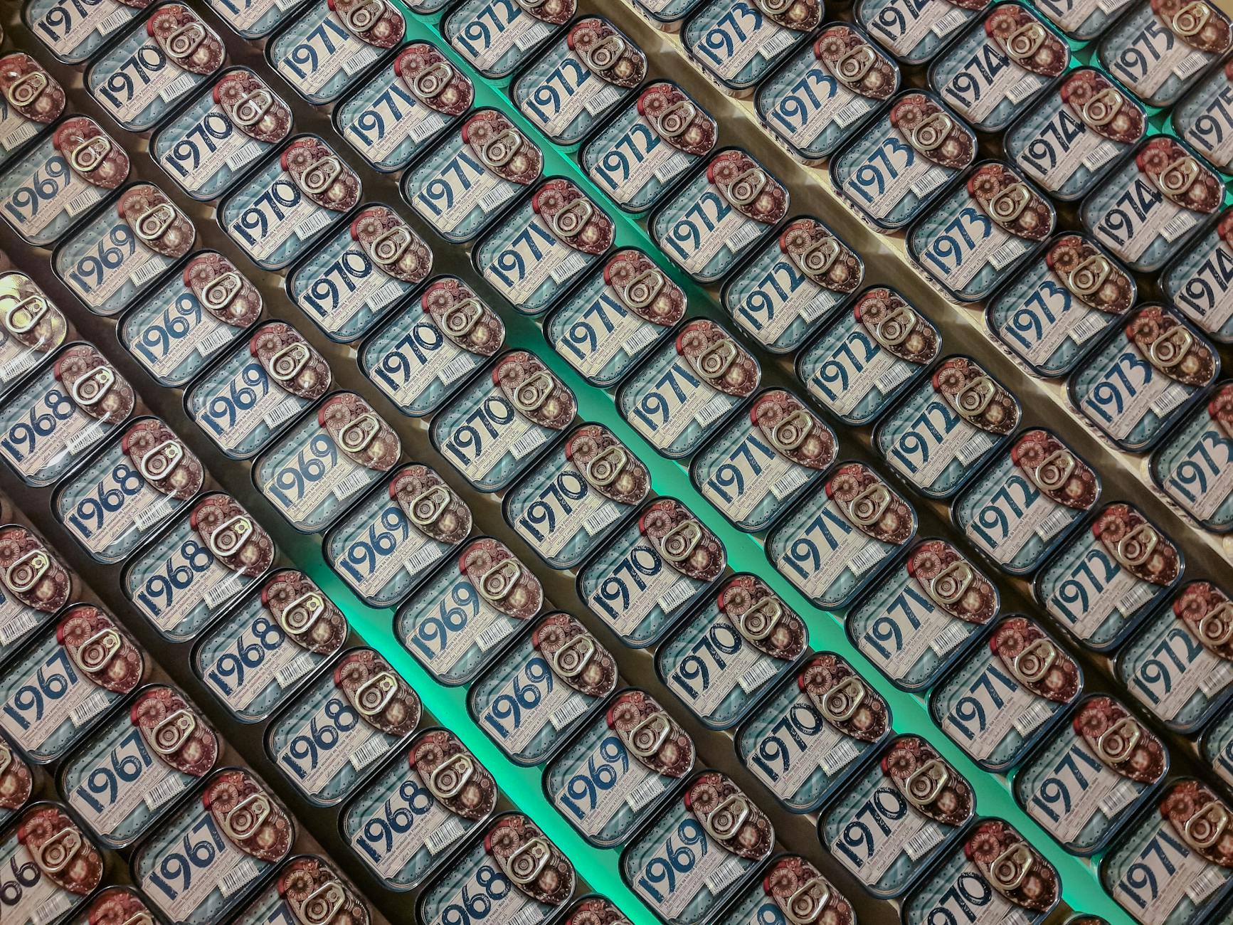 Rows of vintage sardine cans on display, showcasing various years in a Porto shop.