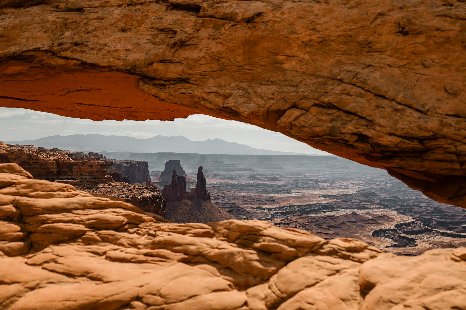 Breathtaking view through Mesa Arch in Utah's Canyonlands National Park at sunset. Marvel at the stunning rock formations.