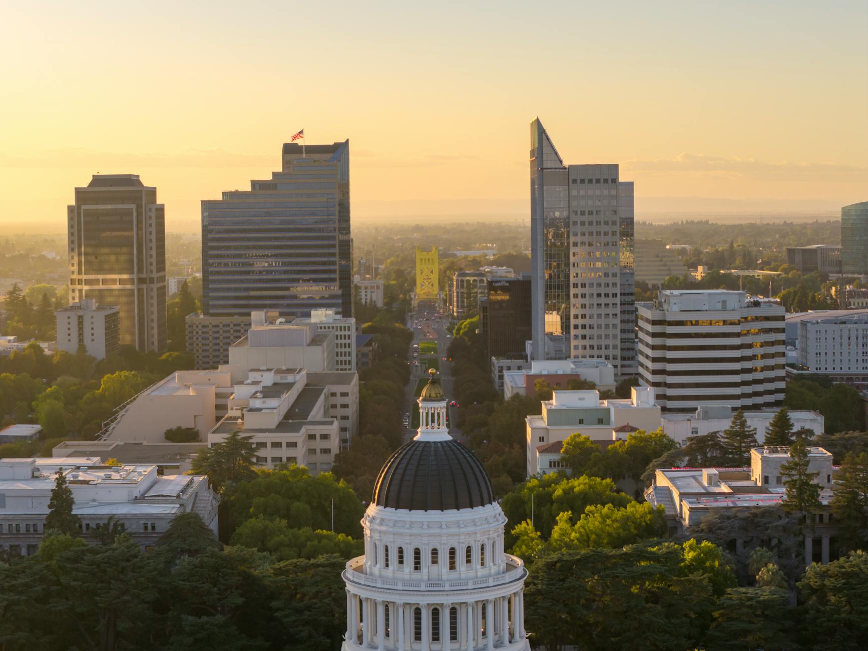 Aerial view of Sacramento skyline featuring the Capitol and Tower Bridge at sunset.