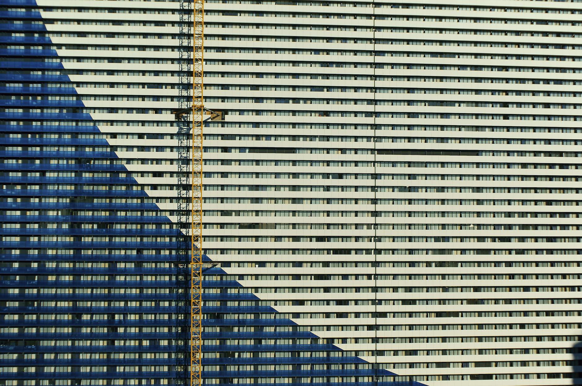 A modern building facade with a geometric pattern and construction crane, shot in Batumi, Georgia.