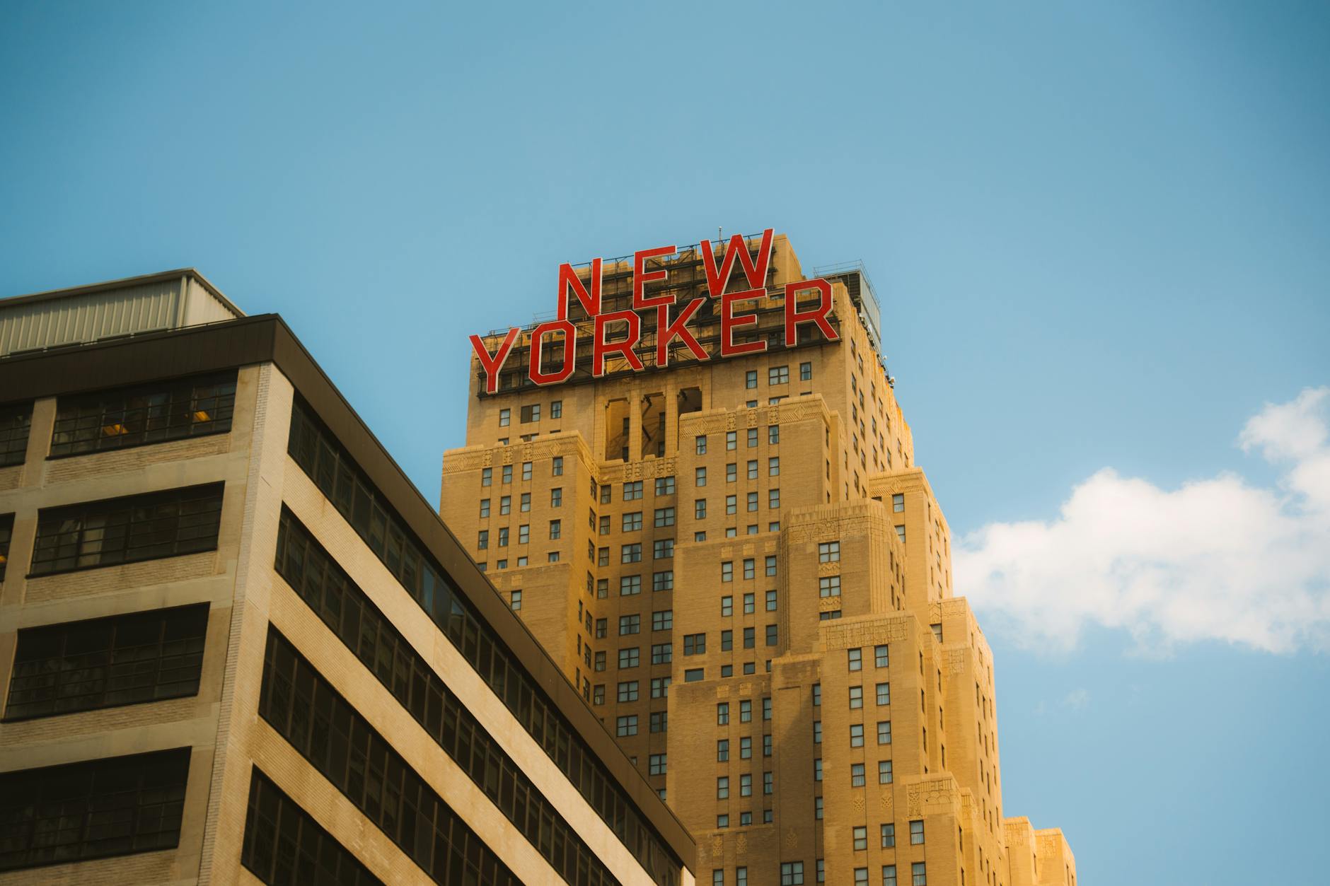 A striking low-angle view of the iconic New Yorker Hotel set against a clear blue sky, capturing urban architecture.
