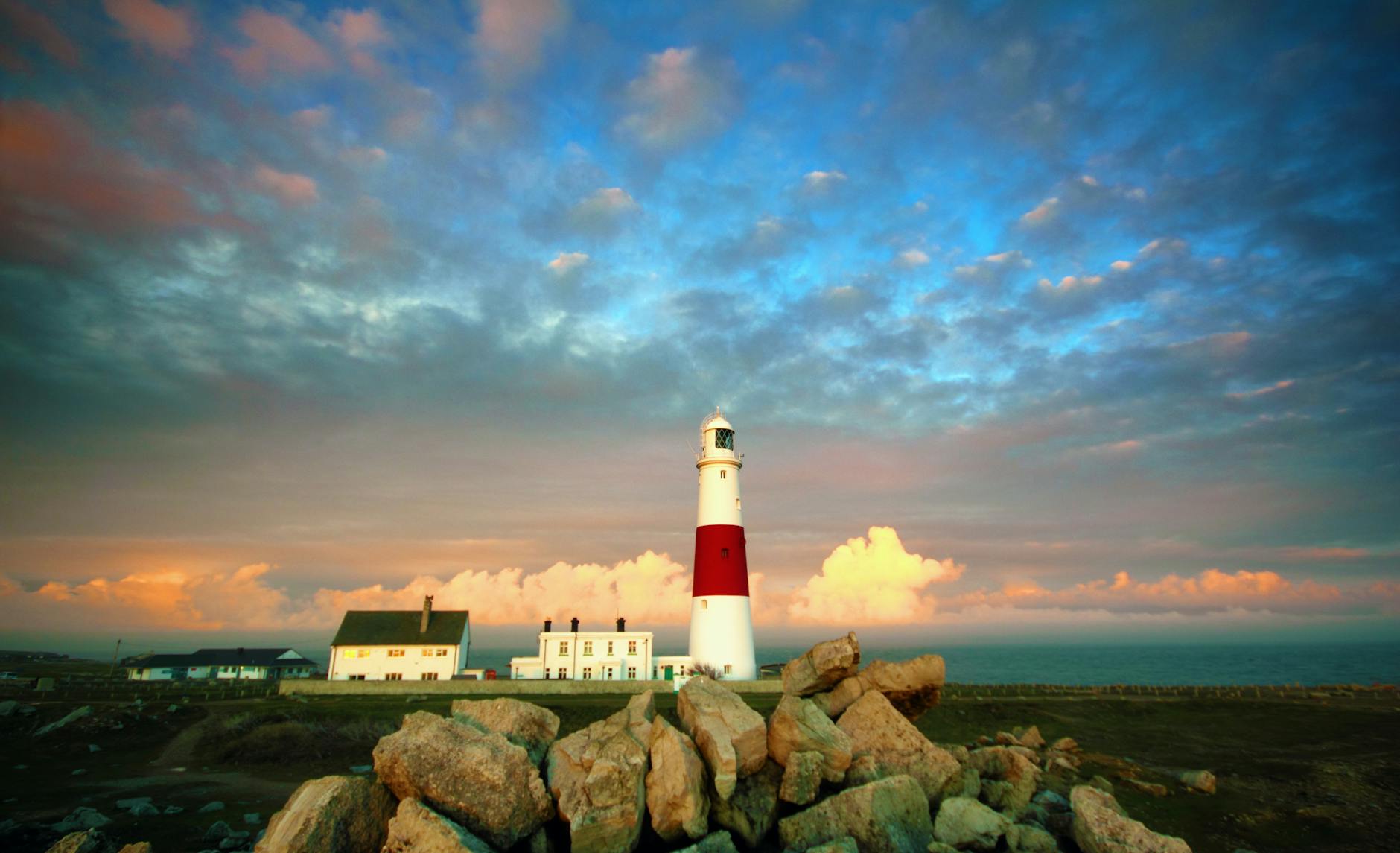 Beautiful sunset view of Portland Bill Lighthouse with dramatic clouds.