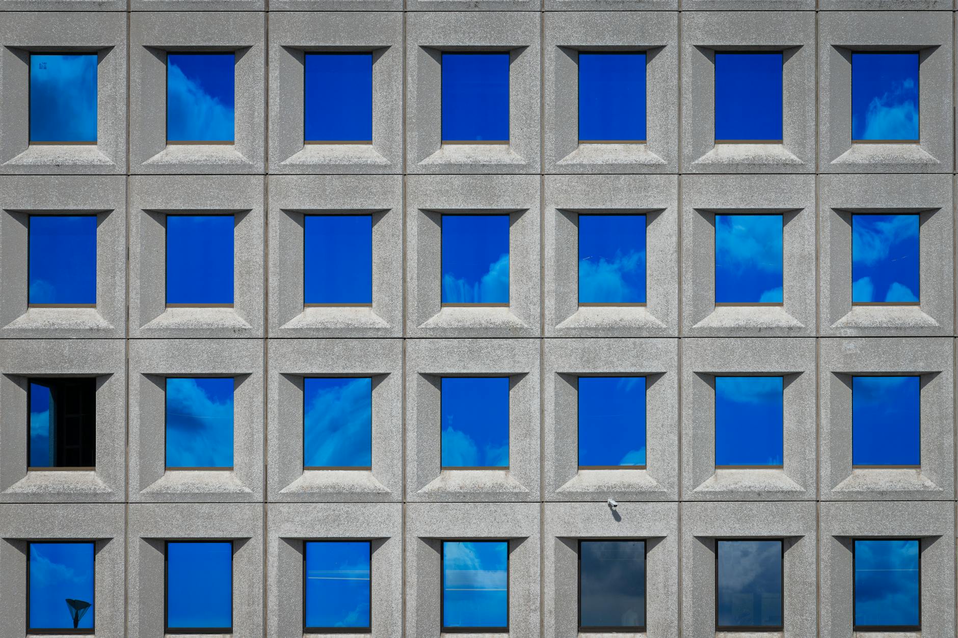 Modern building facade with repetitive windows reflecting the sky in Copenhagen, Denmark.